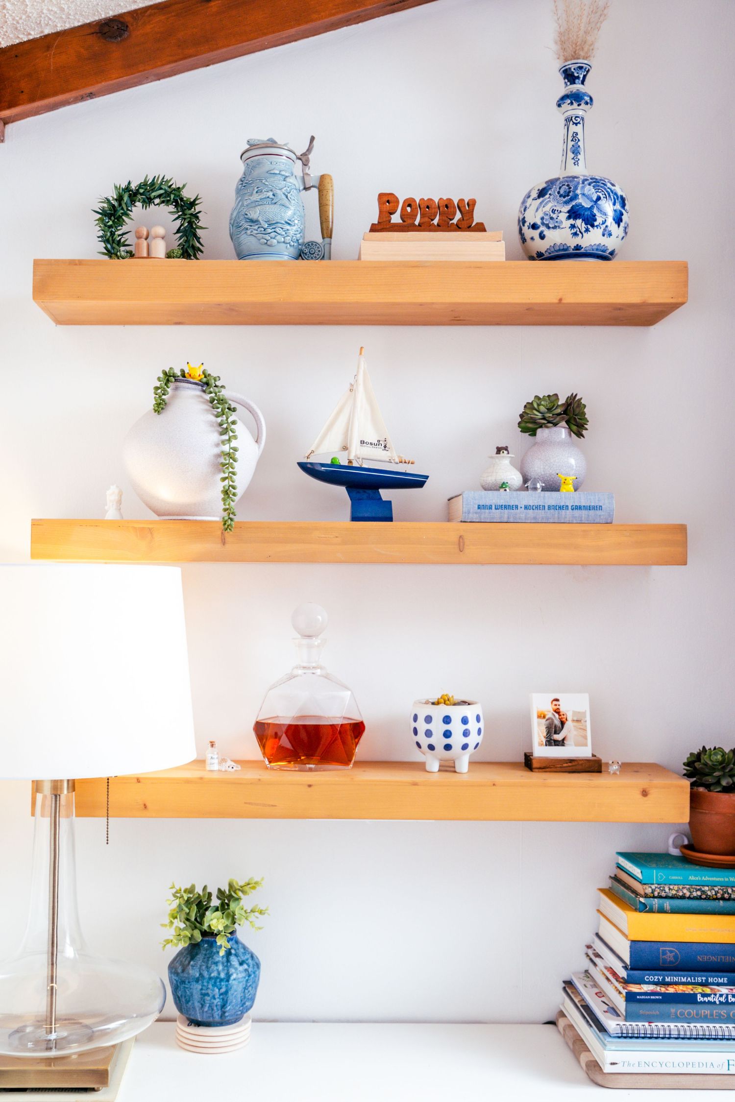 Wooden floating shelves display blue and white pottery, books, and decorative items against a white wall.
