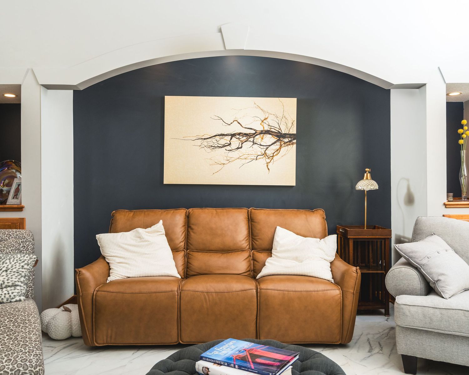 Modern living room interior with dark blue walls, brown leather sofa, and minimalist decor accents.