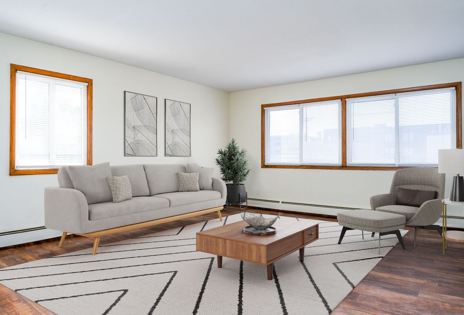 Modern living room featuring a gray sofa, wooden coffee table, geometric rug and natural light from multiple windows.