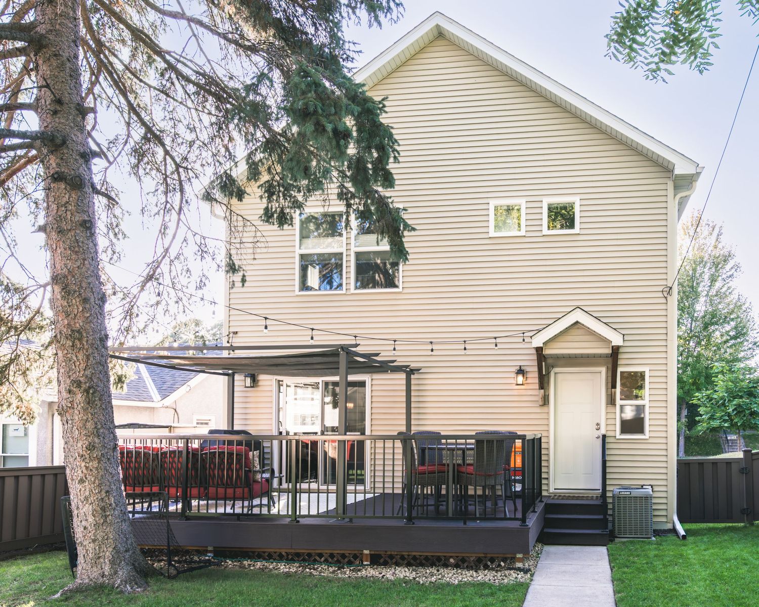 A series of five connected exterior photos showing different angles of a beige residential house with a deck and landscaping.