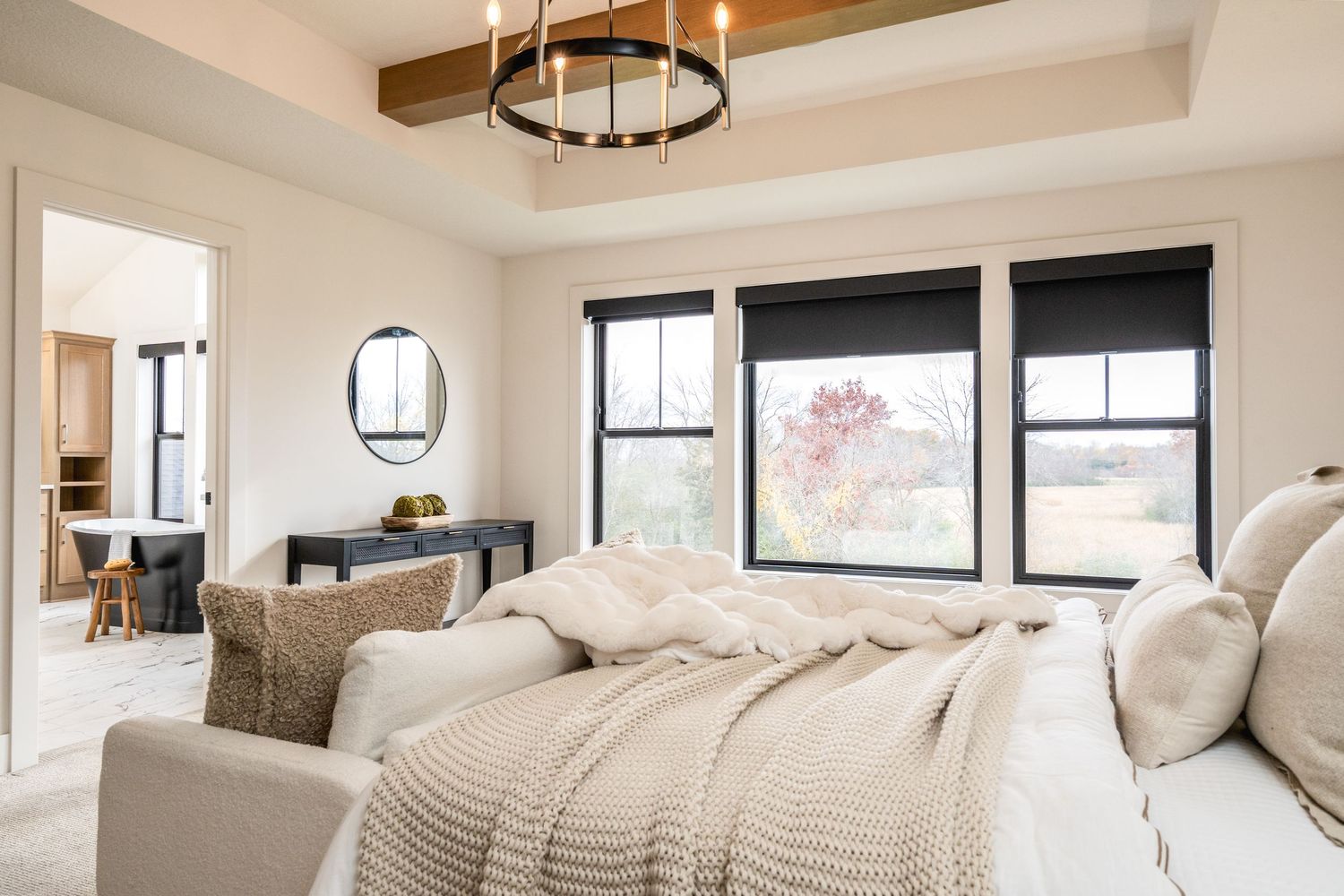 Modern white bedroom interior with wood beam ceiling, pendant light, and large windows offering natural light.