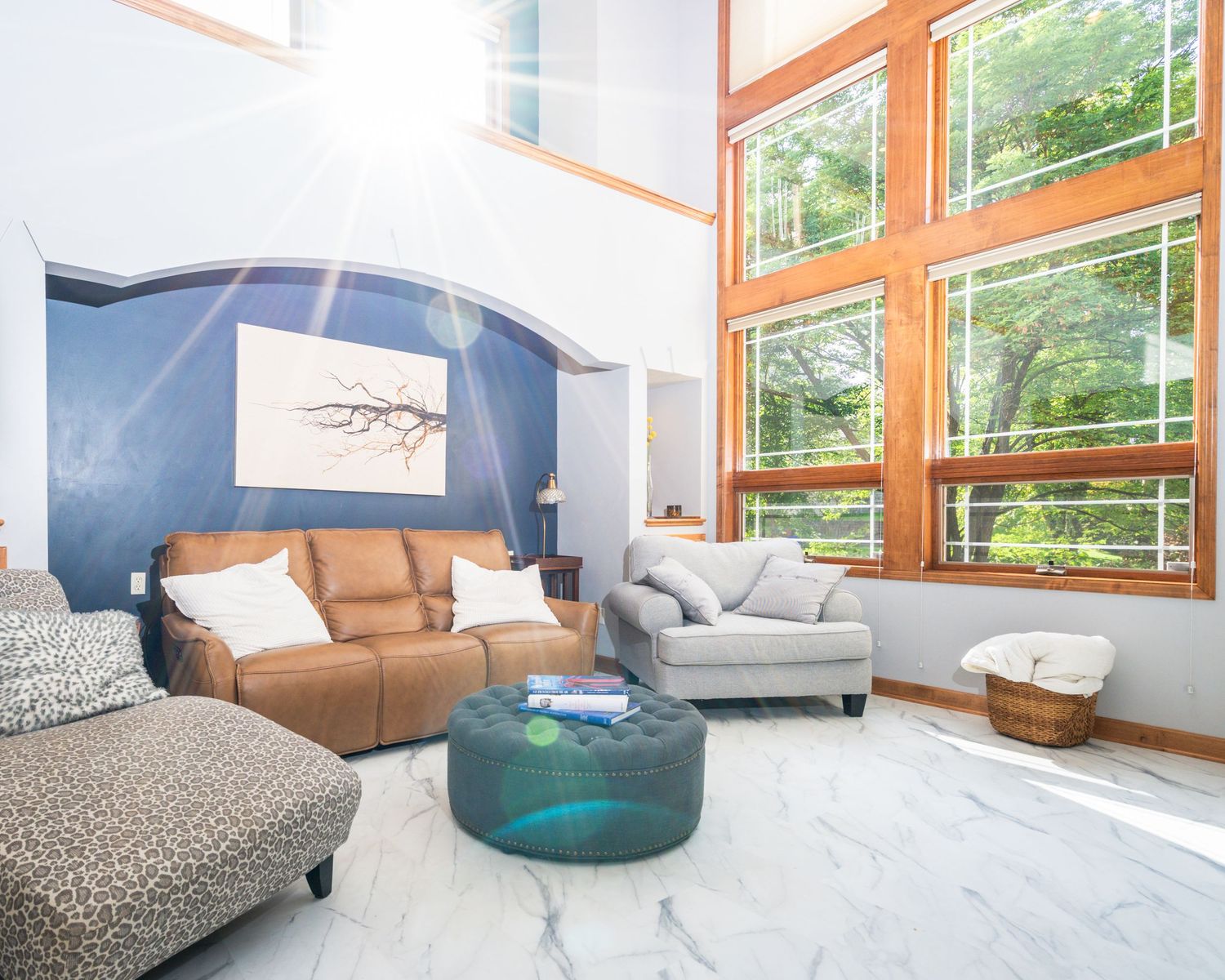 Modern living room with orange-framed windows, gray couch, and bright natural lighting creates an airy atmosphere.