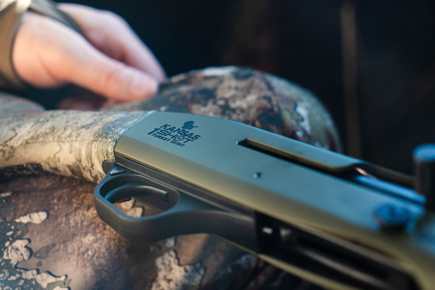 Close-up detail of a black shotgun or hunting rifle against a textured background.