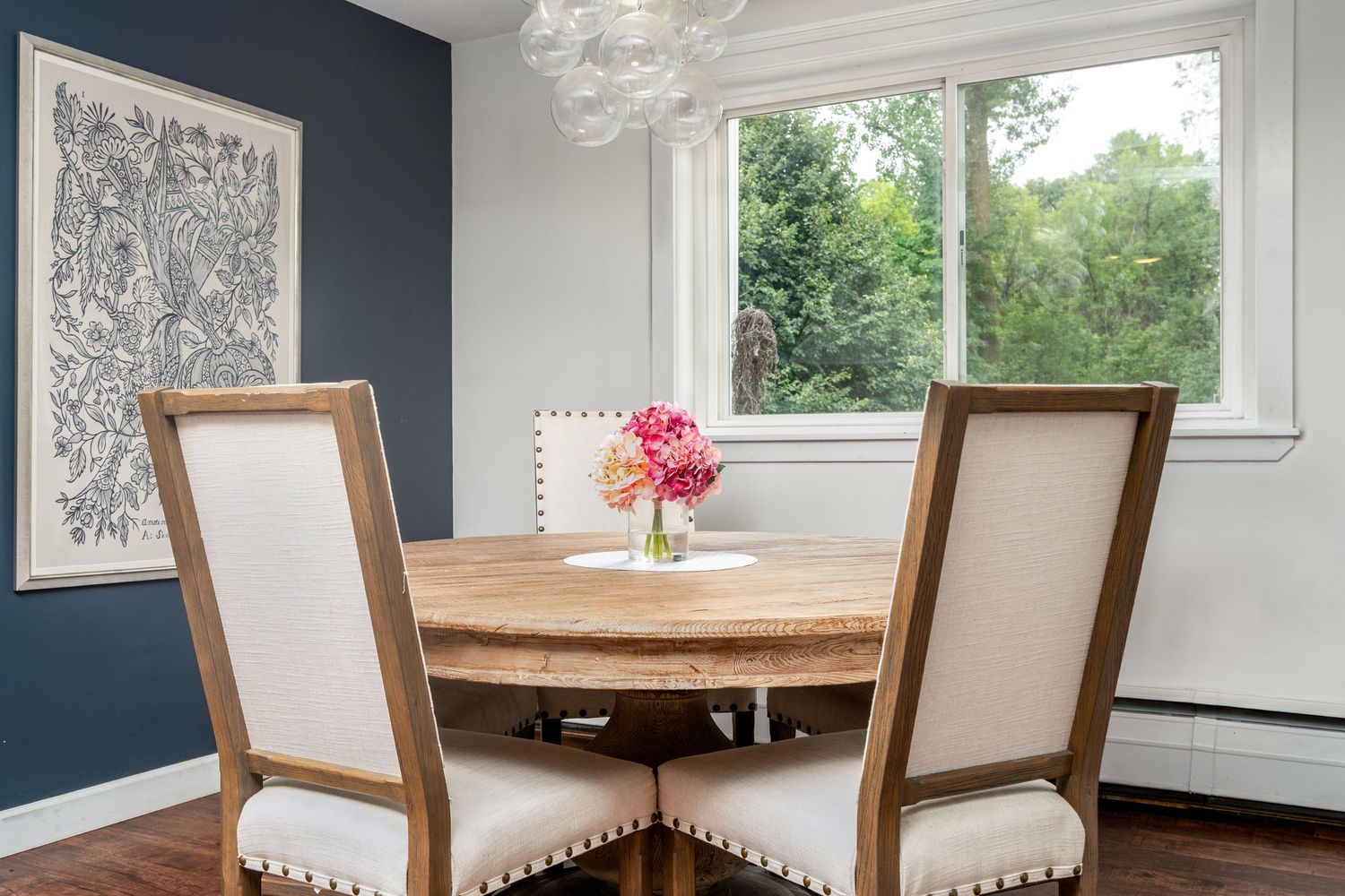 Navy blue accent wall contrasts with white trim in modern dining room featuring upholstered chairs and crystal chandelier.