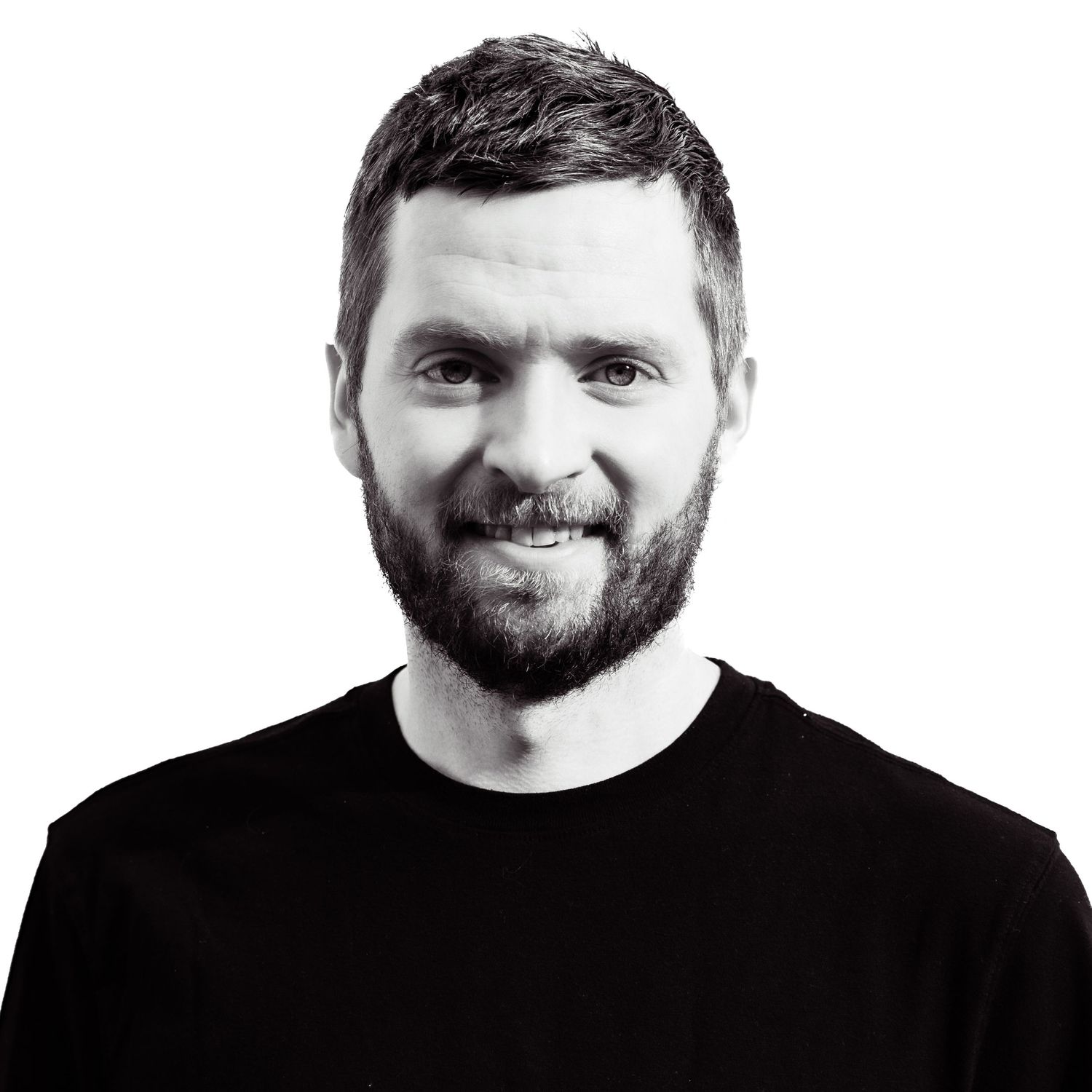 Black and white portrait of a man in dark shirt smiling at camera.