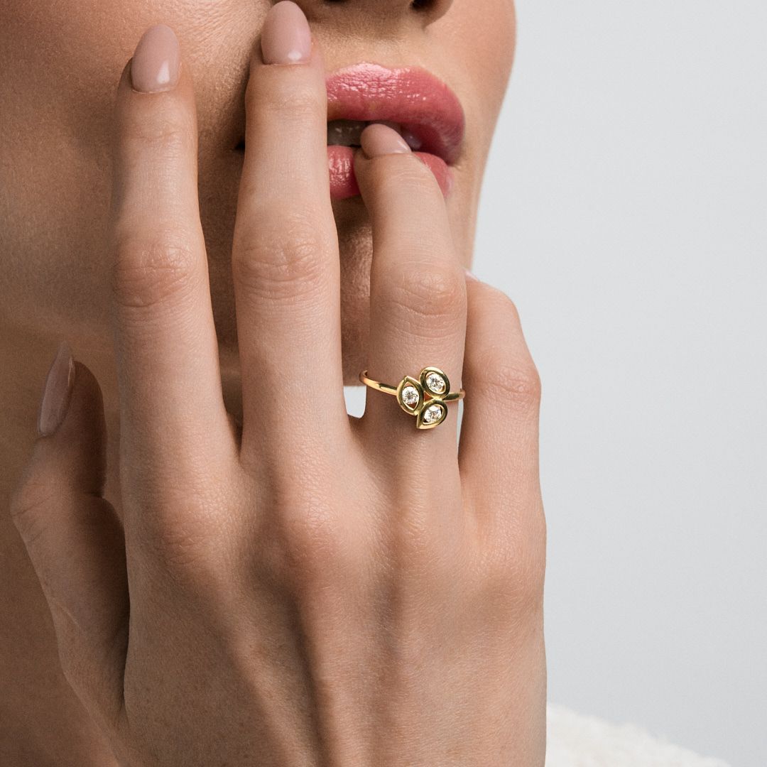 Gold ring with opal and crystal stones worn on finger, elegant jewelry close-up shot.