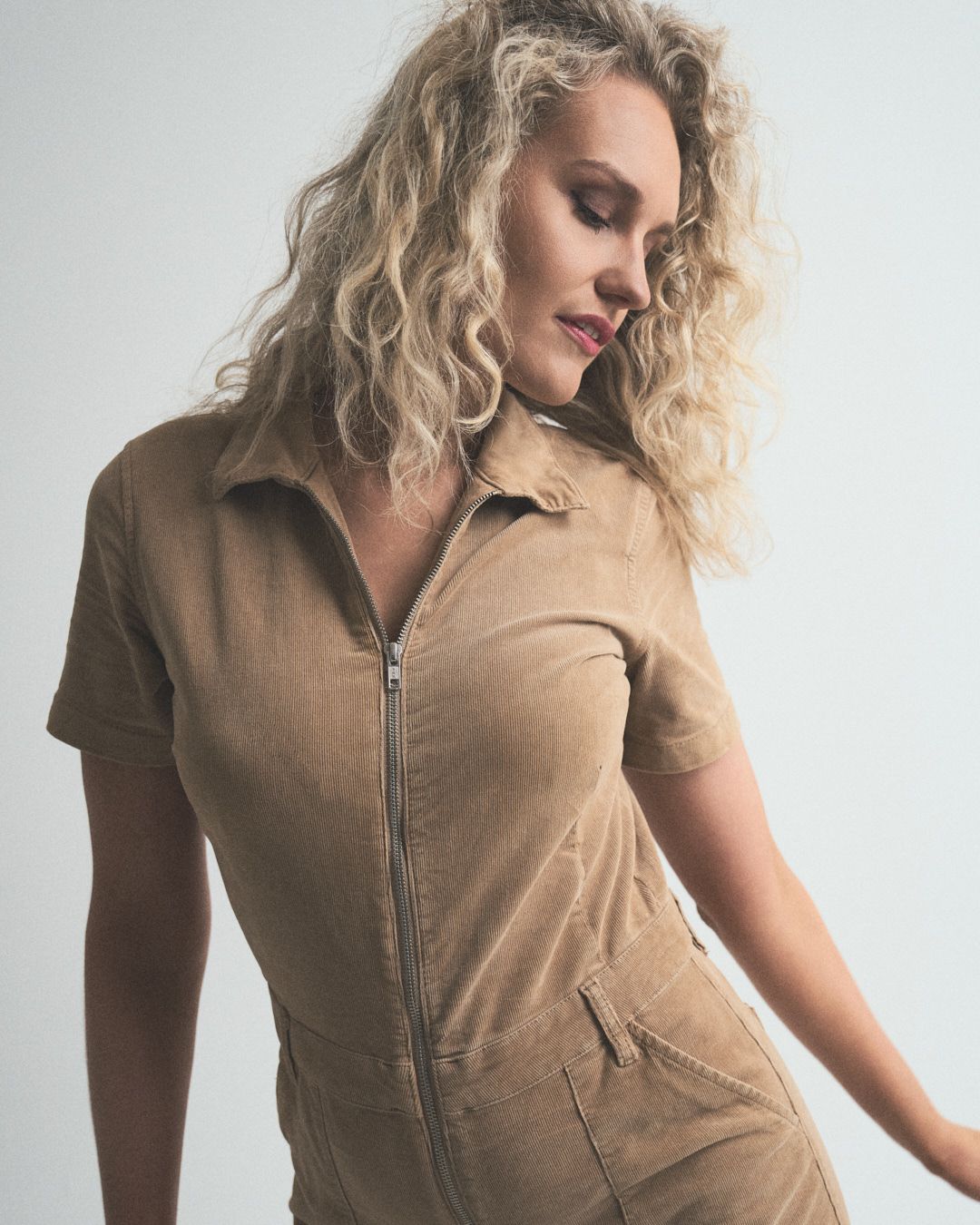Model wearing a beige ribbed zip-up dress with short sleeves and collar in various poses against white background.