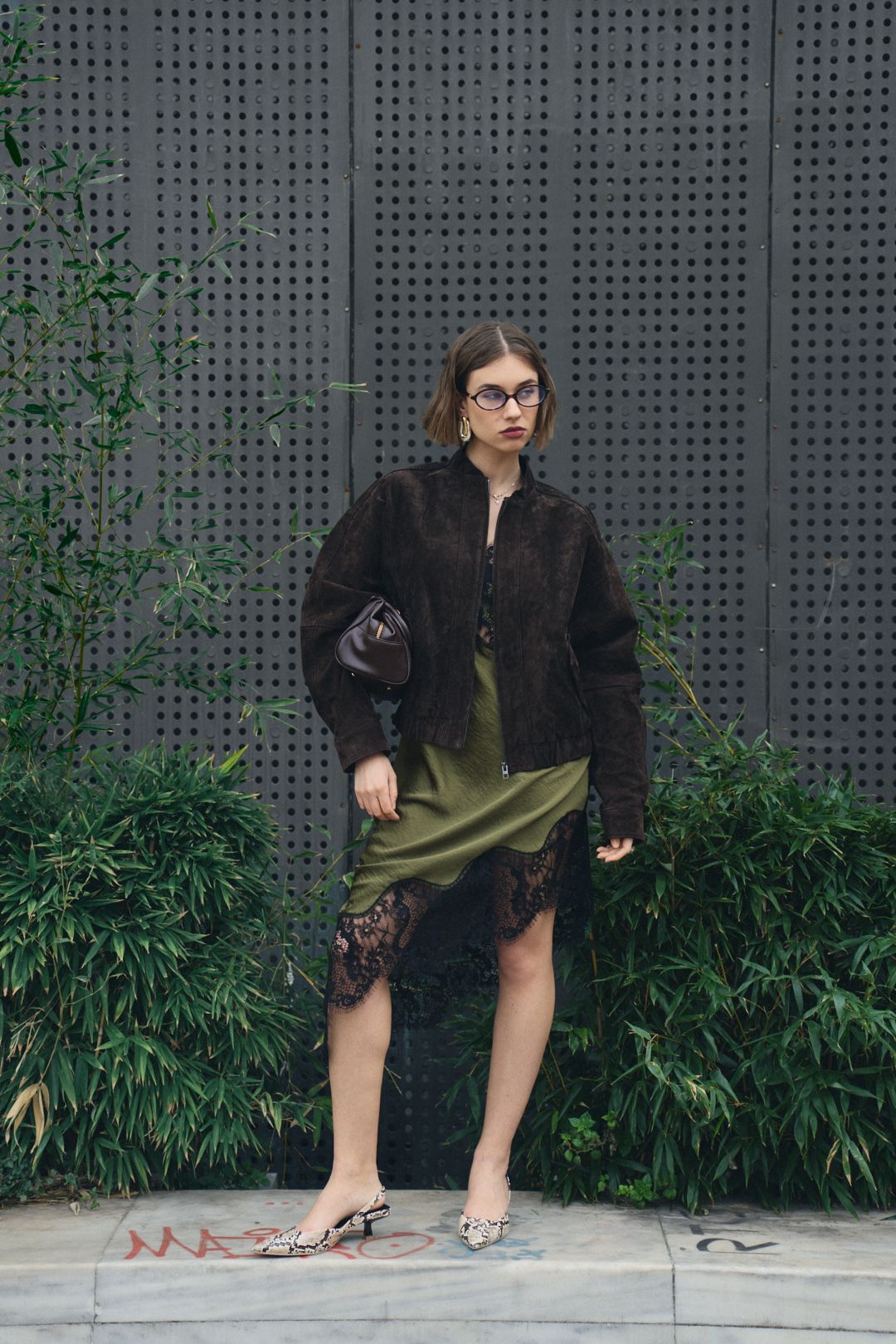 A series of shots showing someone in dark clothing seated on a concrete ledge near green foliage.