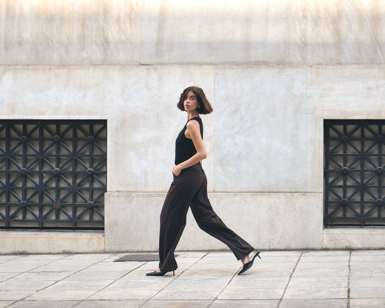 A figure in black workout attire performs a dynamic running sequence captured across five sequential frames against a white wall.