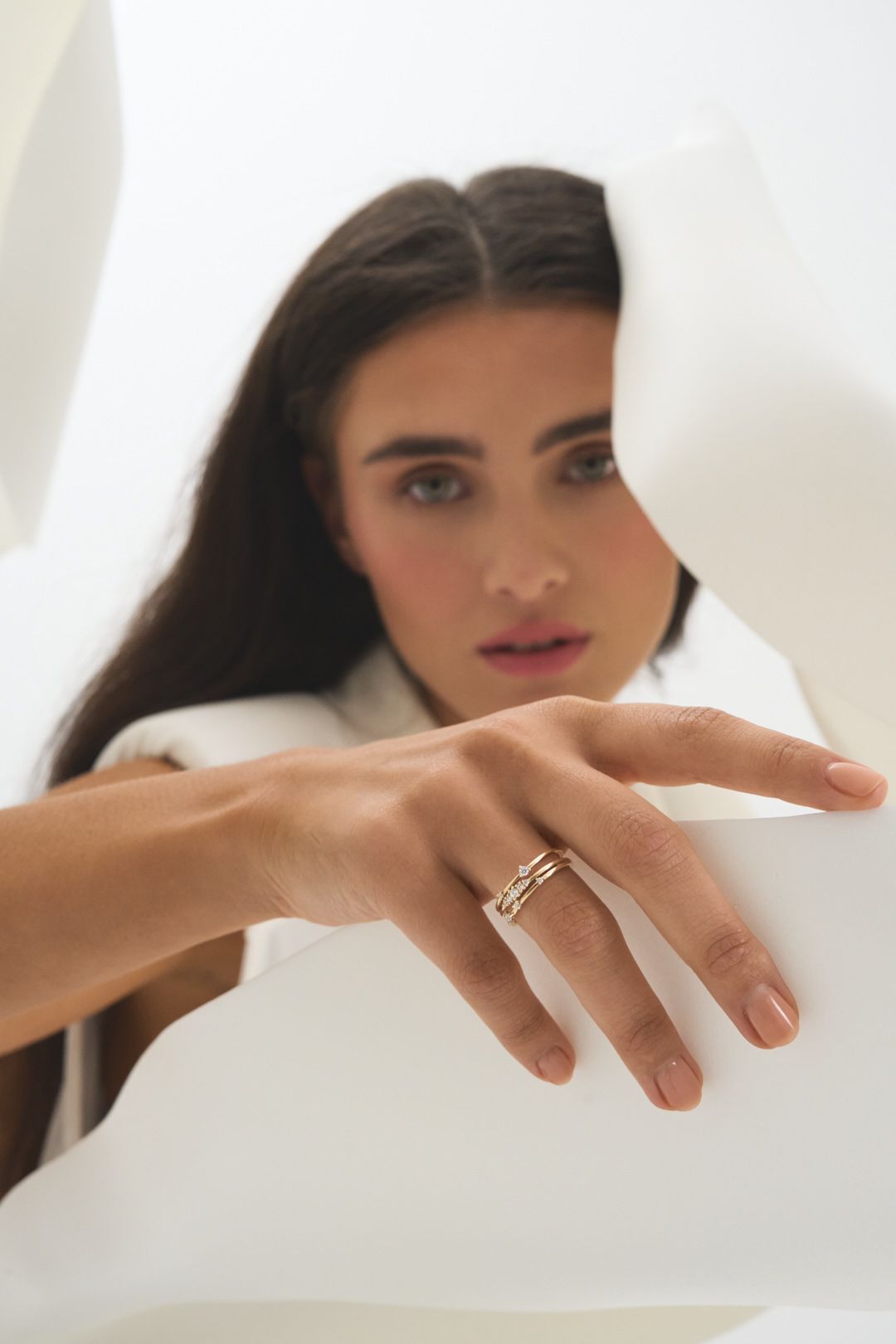 Close up shot of hands with rings against a bright white background.