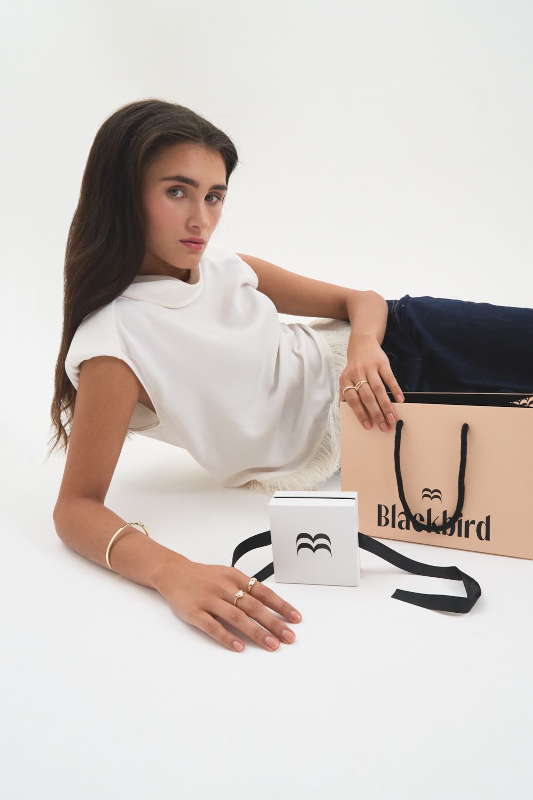 Fashion product photo with white shirt, navy pants, shopping bag and branded coffee mug on white background.
