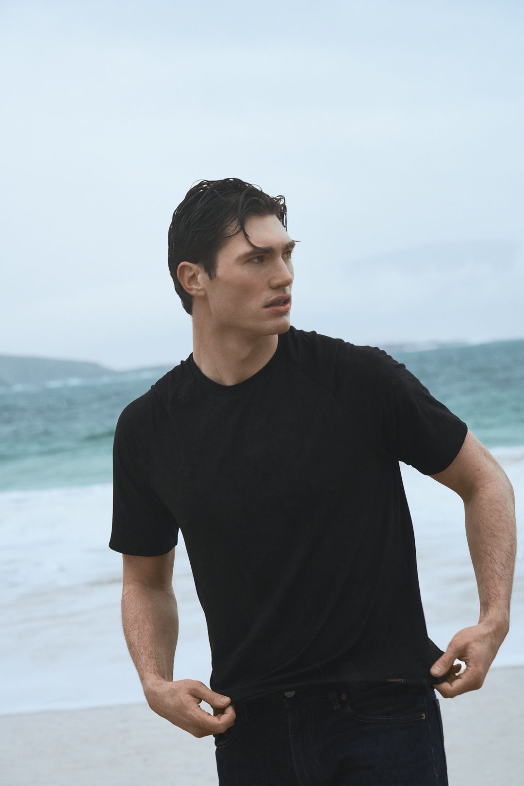 A person wearing a black t-shirt stands against a blurry ocean backdrop in a series of connected poses.
