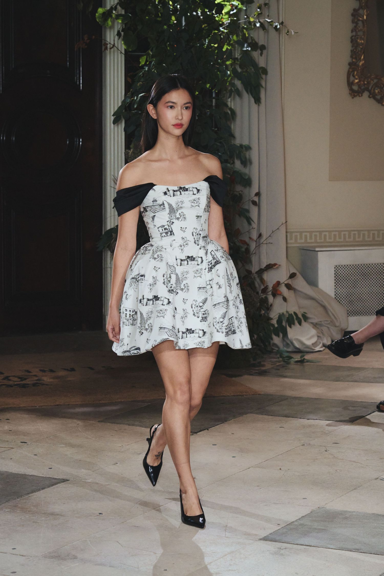 A person in a black and white floral dress and black heels strikes dynamic poses in a series of fashion photographs.