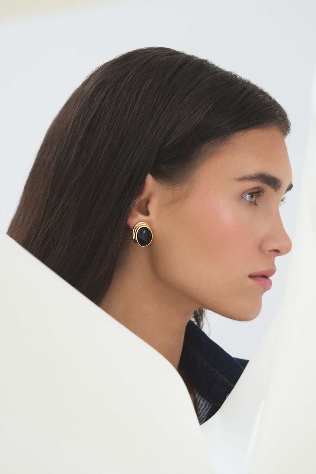 Profile views of a model wearing a black turtleneck and small hoop earring against a white background.