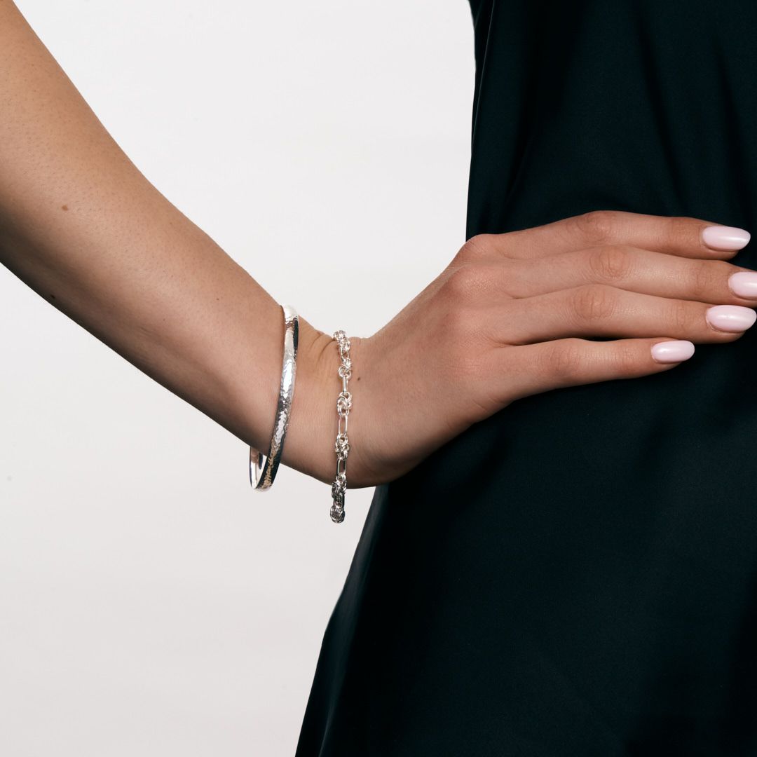 A series of hands with silver jewelry shown from different angles displaying elegant bracelets and rings.