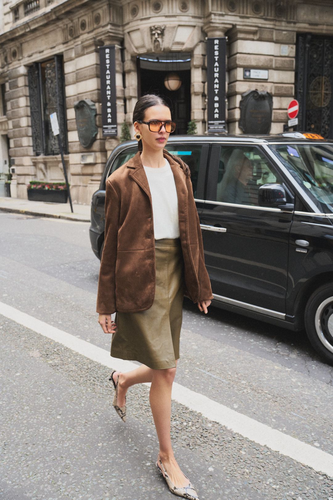 Street style fashion featuring brown suede jacket paired with olive skirt and neutral accessories.