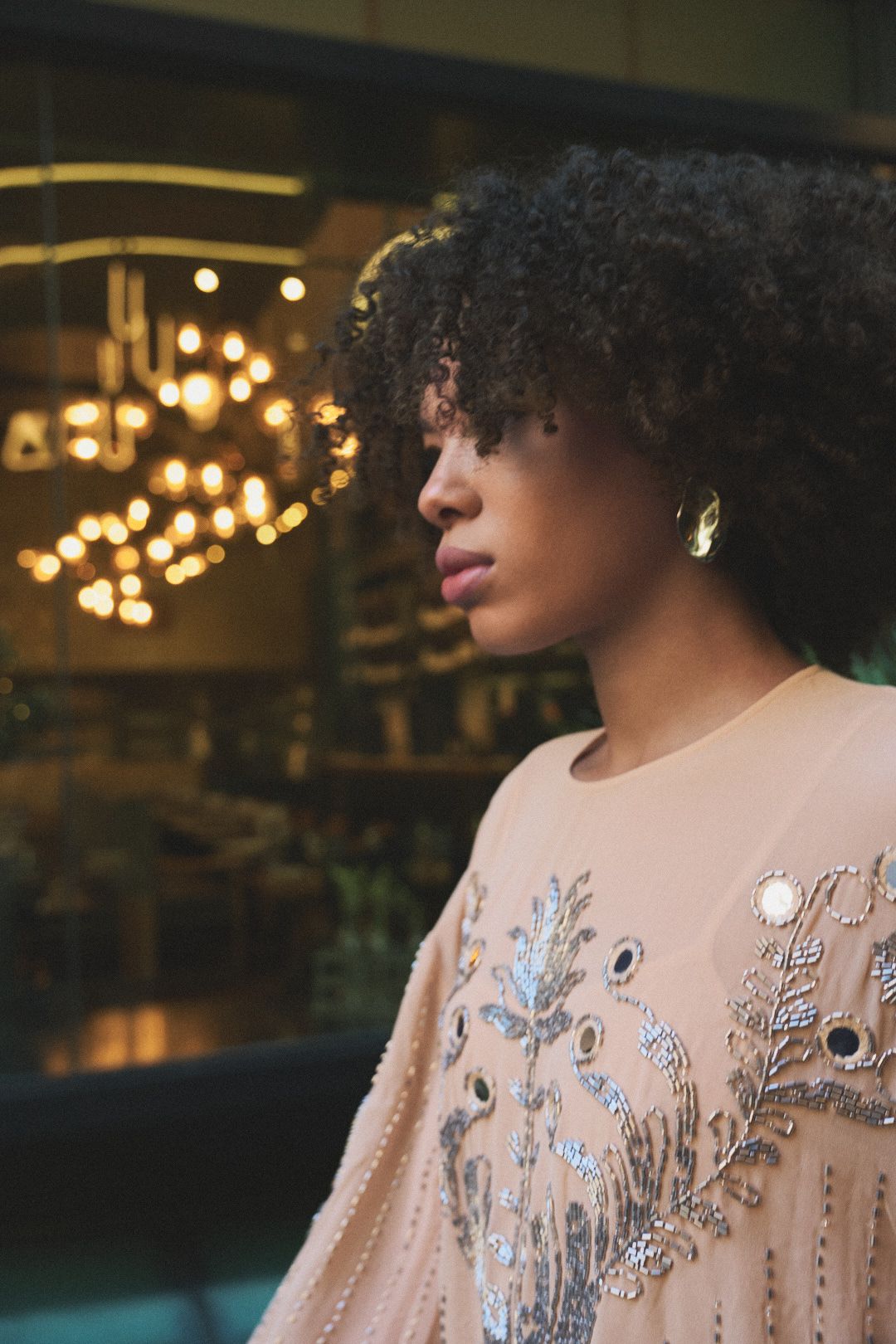 A close-up profile view shows intricate beaded details and embellishments on a blush-colored evening gown.
