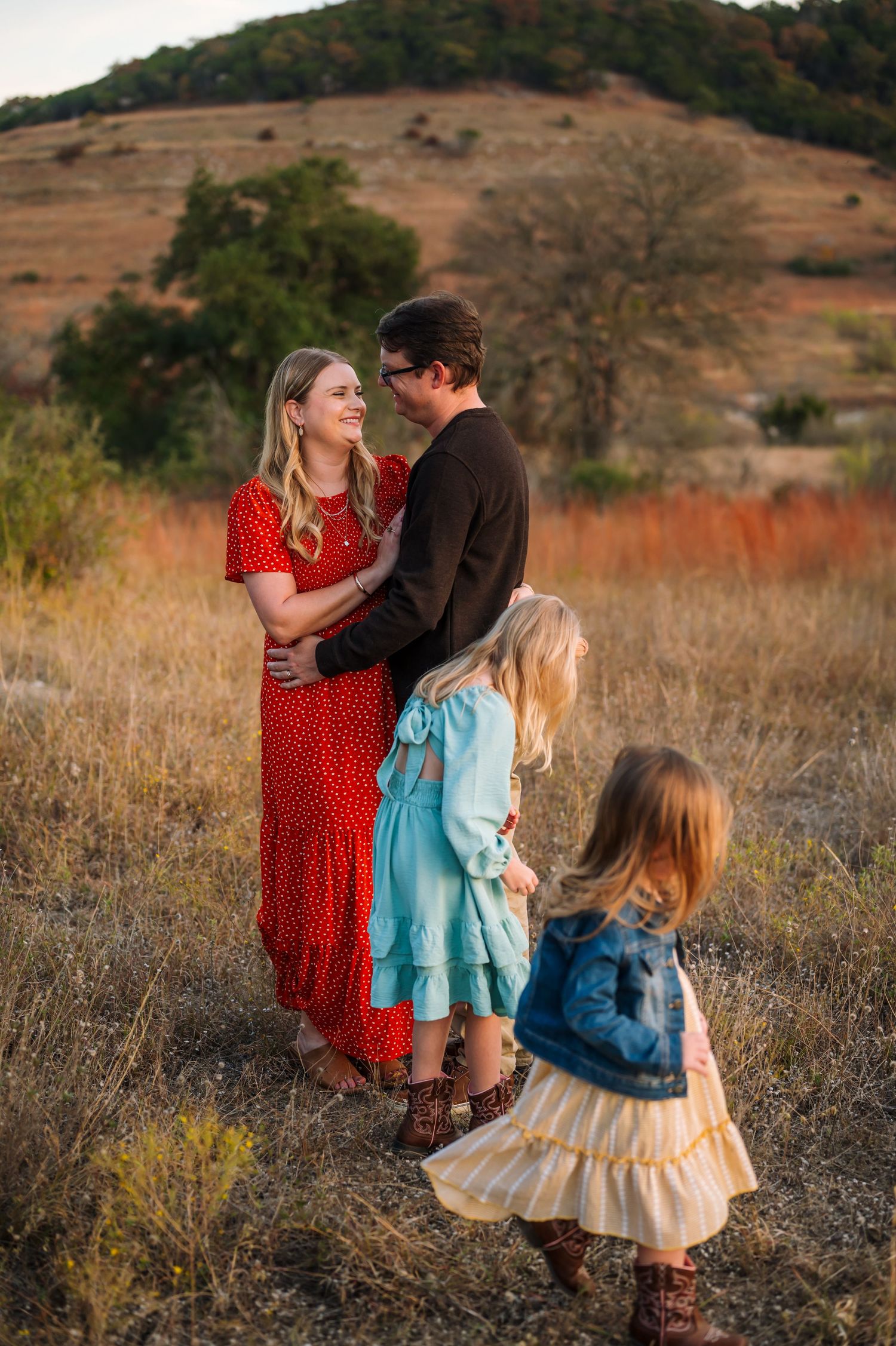 A family shares an intimate moment together in a golden field during sunset.