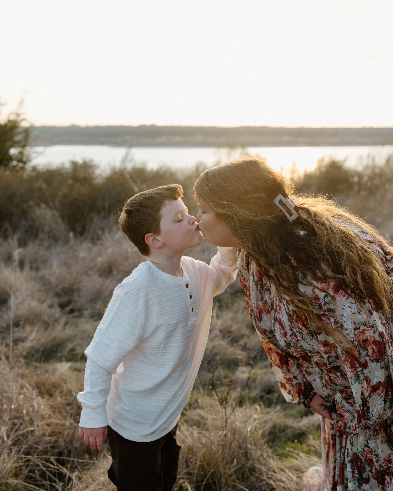 A tender moment between parent and child at sunset in a natural outdoor setting.