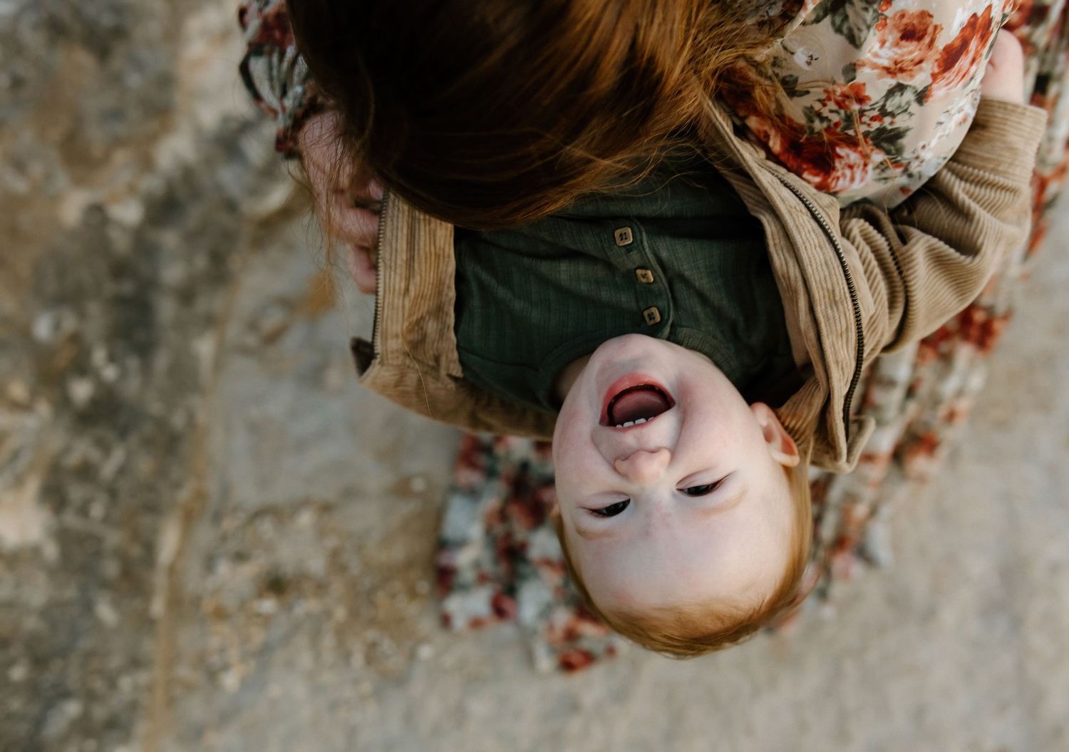 A joyful smile captured from above against a textured rock background.