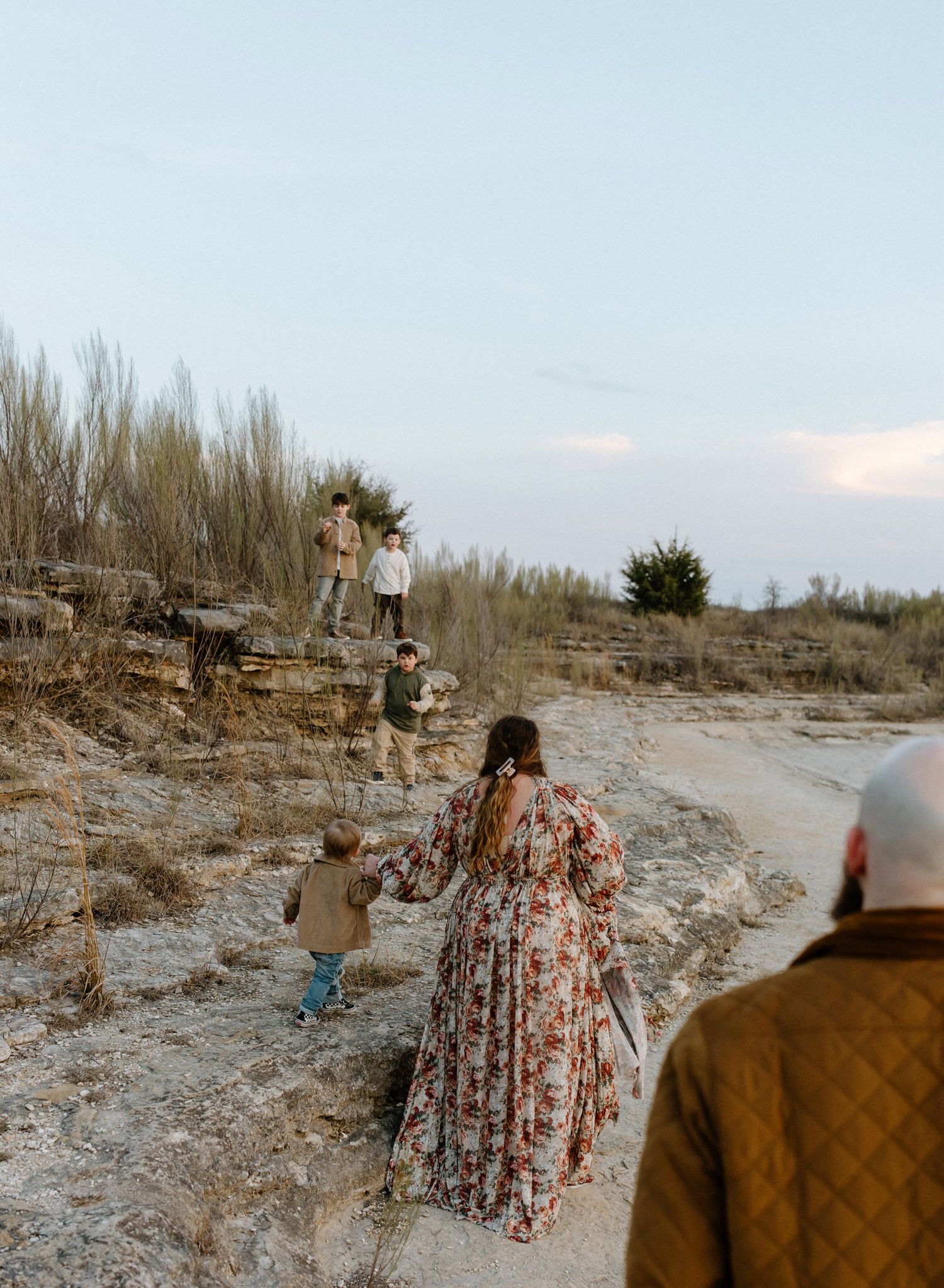 Family members climb rocky terrain near water during an outdoor adventure.