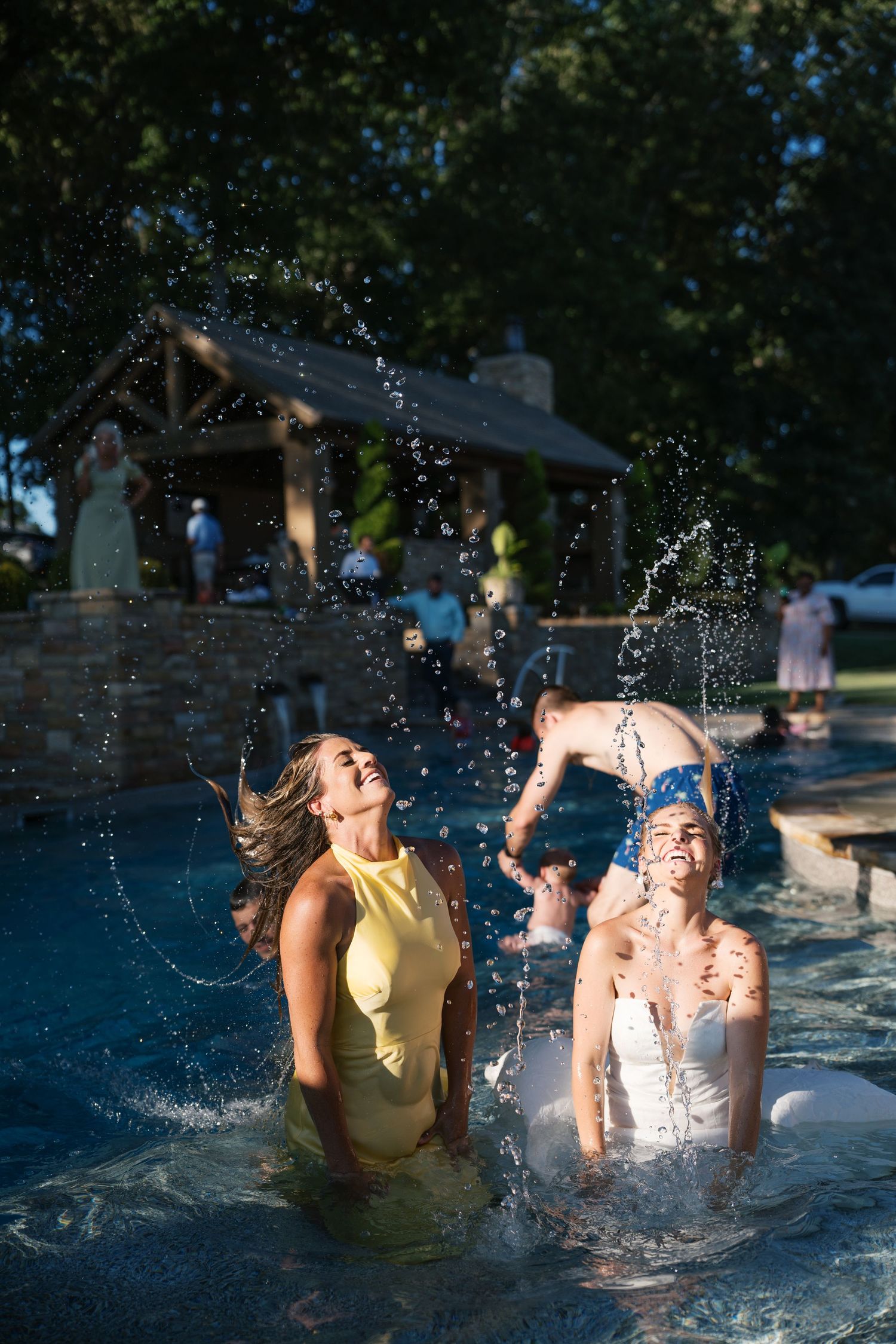 Two people splash and play together in refreshing blue pool water on a sunny summer day.