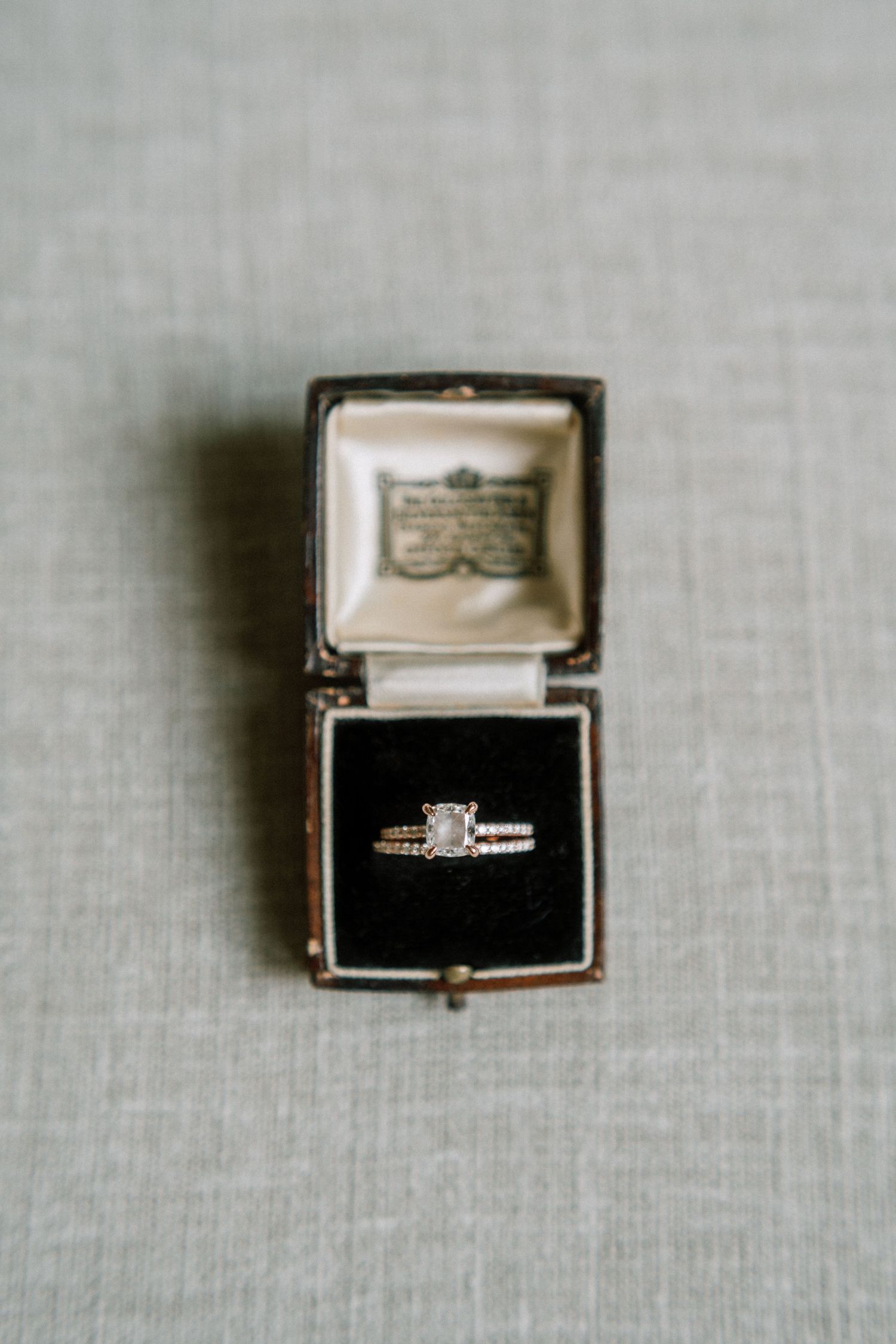 Close-up of a diamond engagement ring in an antique black box on light gray fabric. Kirstie Whitaker Photography