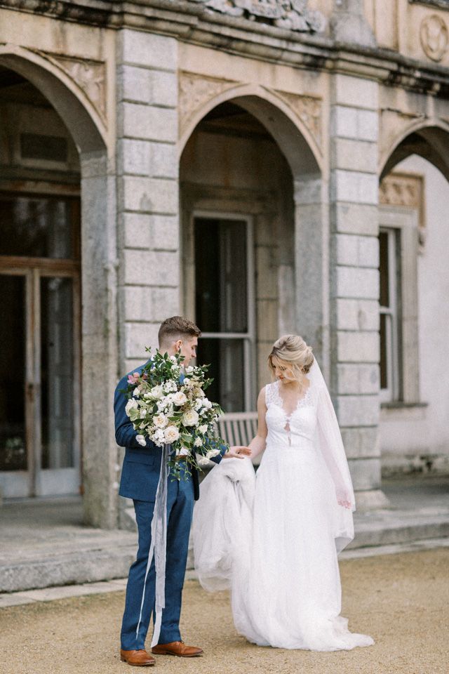 Elegant outdoor wedding scene at a historic stone building with beautiful floral bouquet and romantic details.