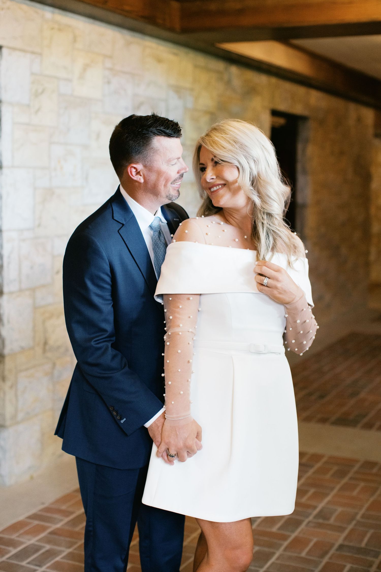 Three romantic wedding photos show an intimate moment between a couple in formal attire against a stone wall backdrop.