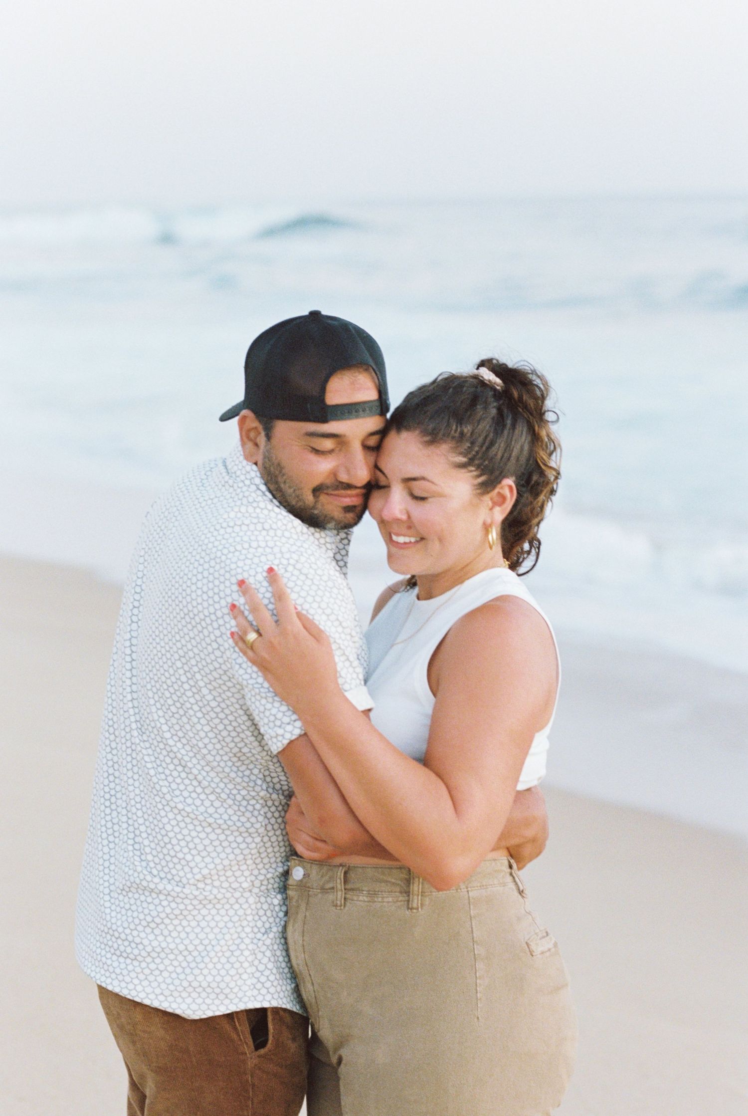 Couple sharing tender moment on Mexico beach while showing off engagement ring. Kirstie Whitaker Photography