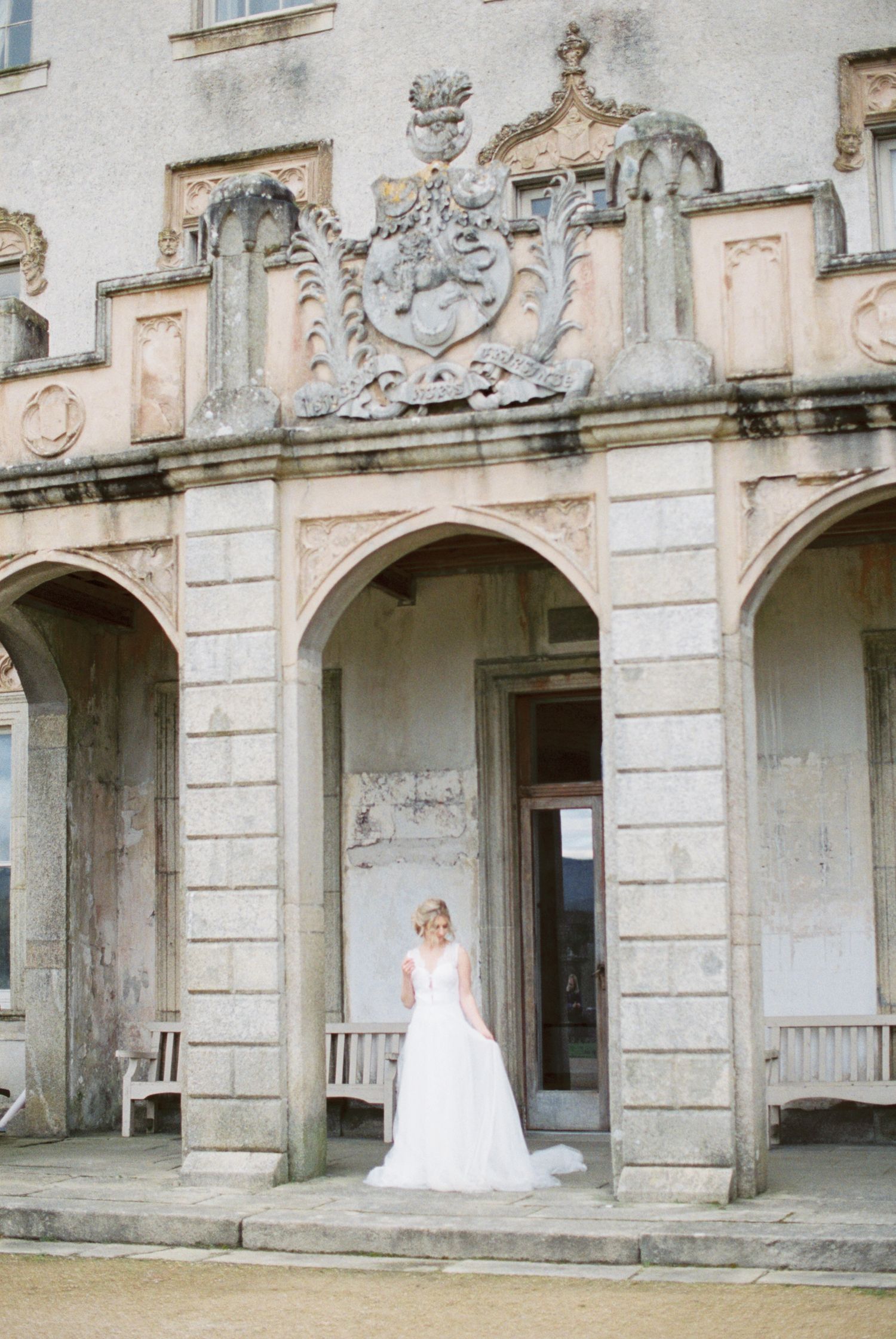 Elegant stone archway entrance of a historic building with ornate architectural details and decorative crest above.