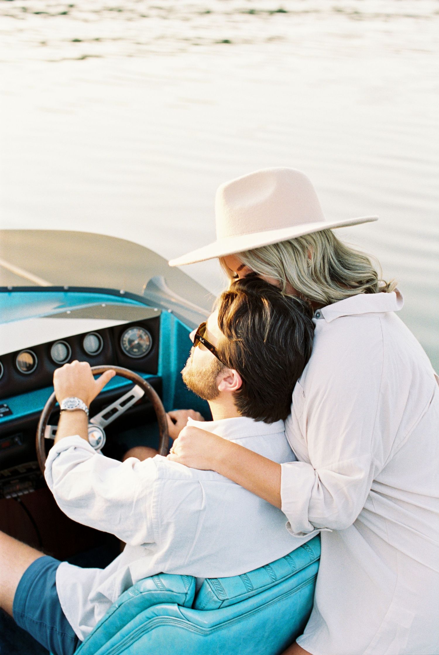KY Romantic couple sharing an intimate moment in a vintage turquoise convertible car while wearing light colored clothing.