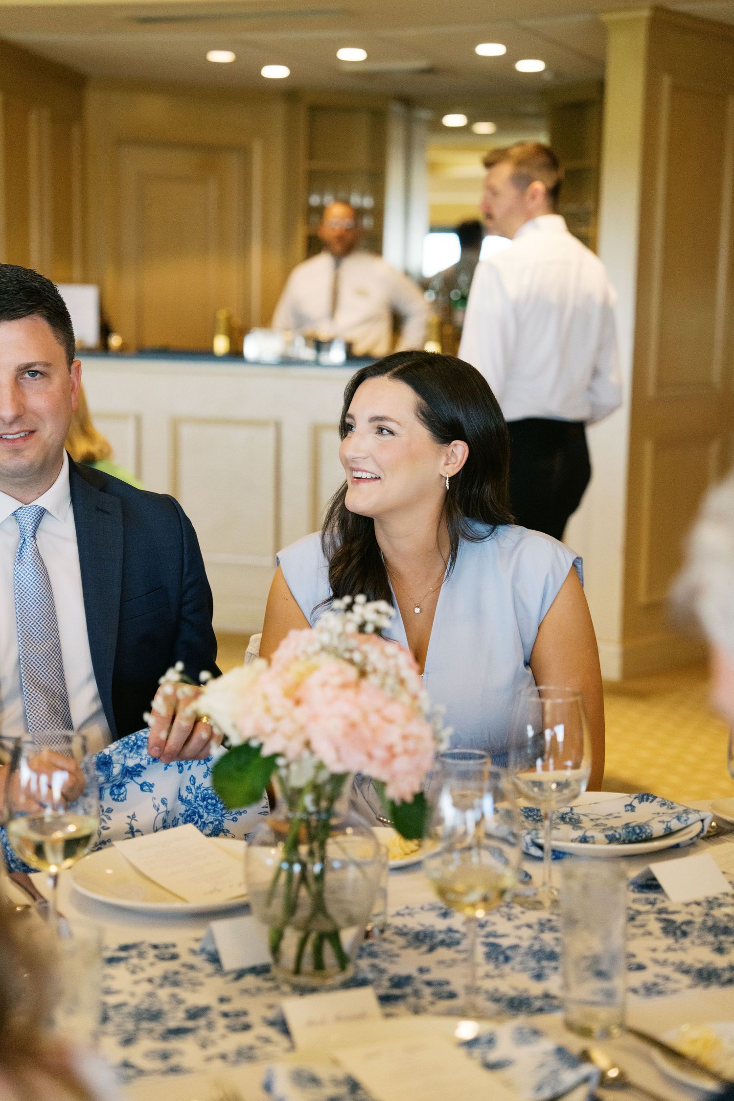 Elegant wedding reception table settings with blue and white decor and soft pink floral centerpieces in a banquet hall.