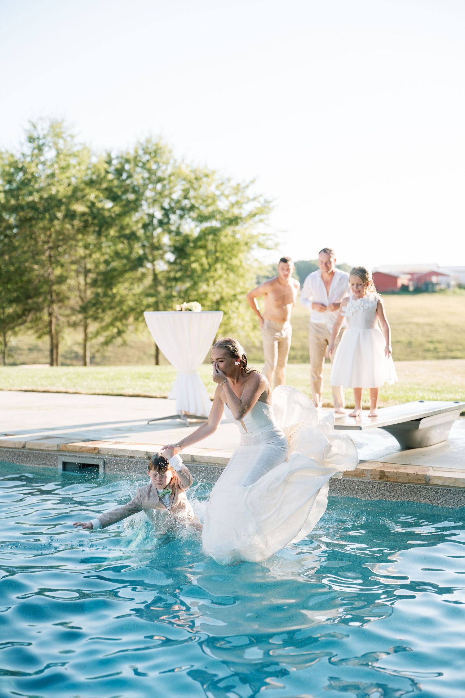 A sequence of four photos showing someone in a white dress falling into a swimming pool during a sunny day.