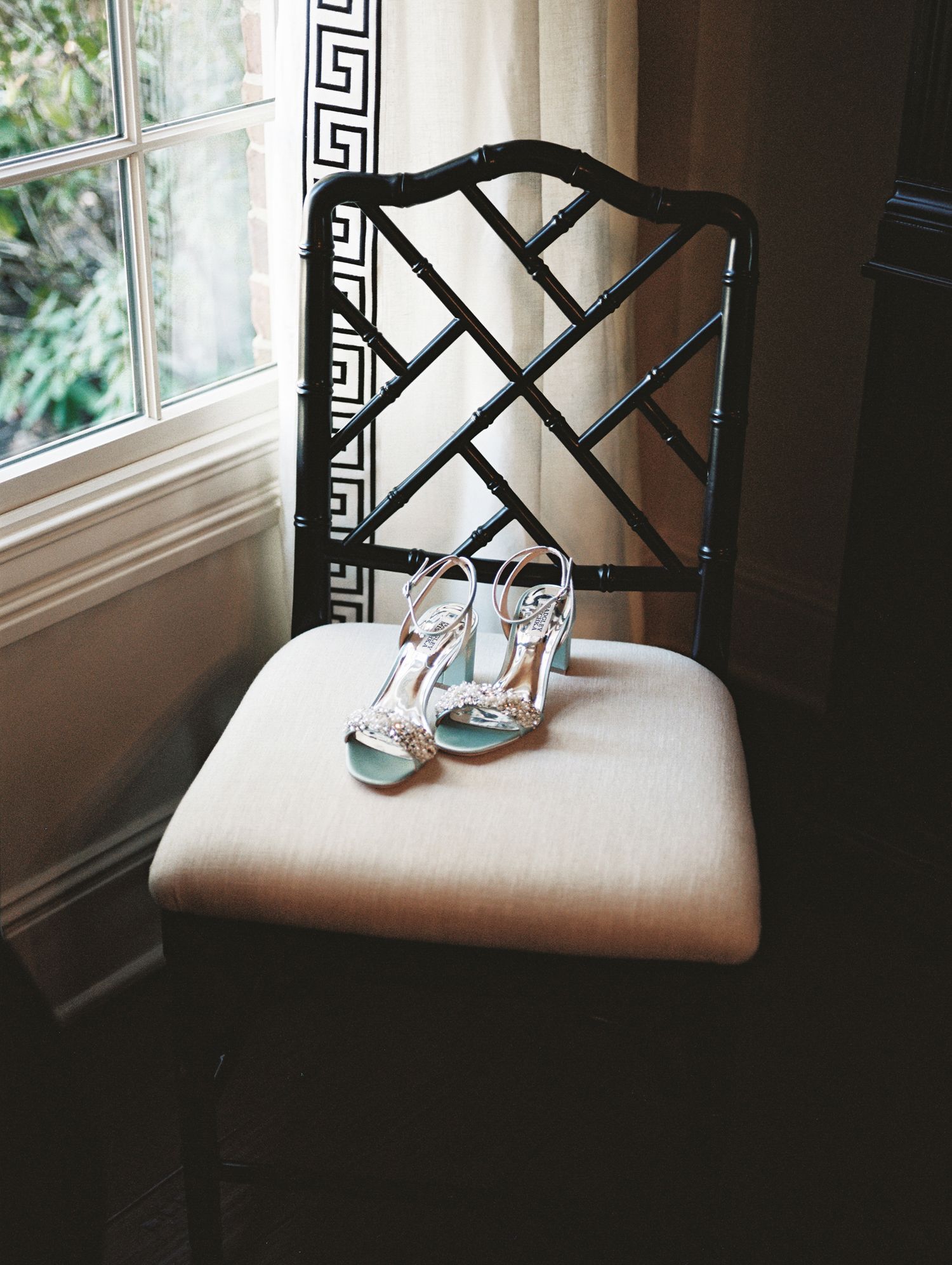 Elegant bridal shoes on black chinoiserie chair against window. Kirstie Whitaker Photography