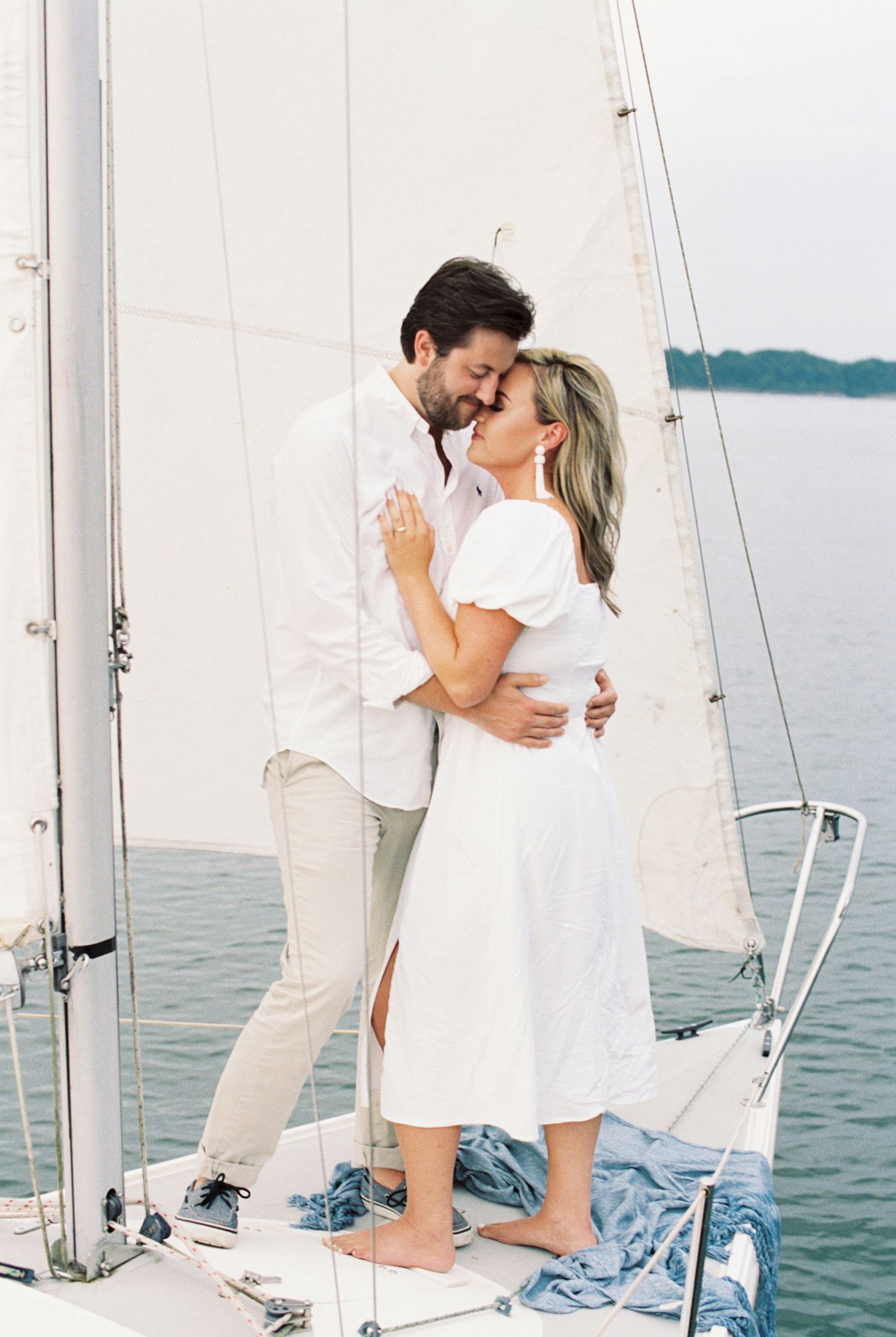 Romantic moment between couple dressed in white on sailboat deck. Kirstie Whitaker Photography