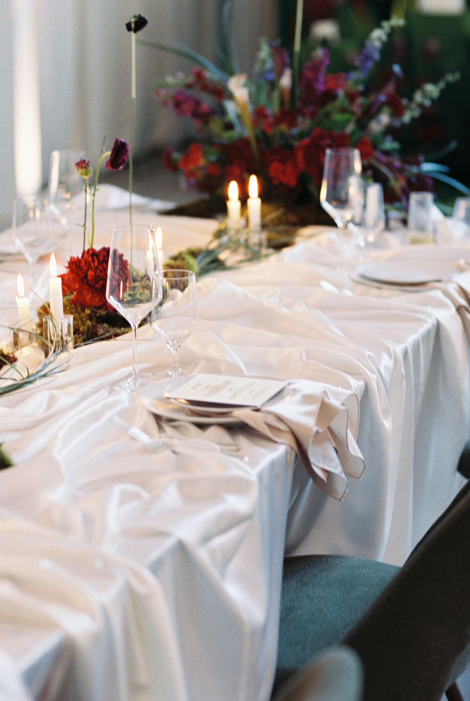 Elegant banquet tables set with white linens, wine glasses, and glowing candles create an upscale dining atmosphere.