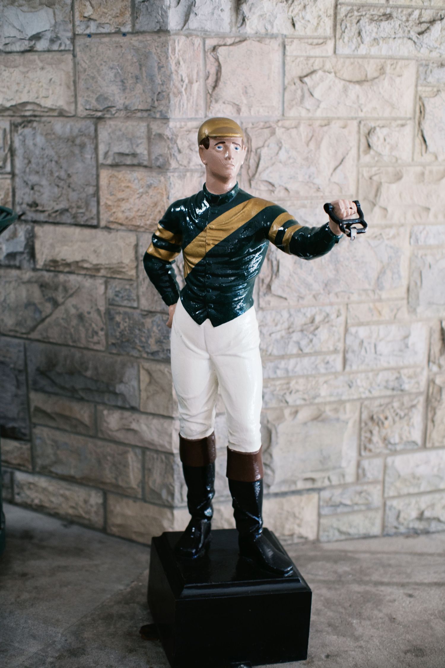 A series of photos showing an antique baseball player lawn jockey statue displayed against a stone wall.