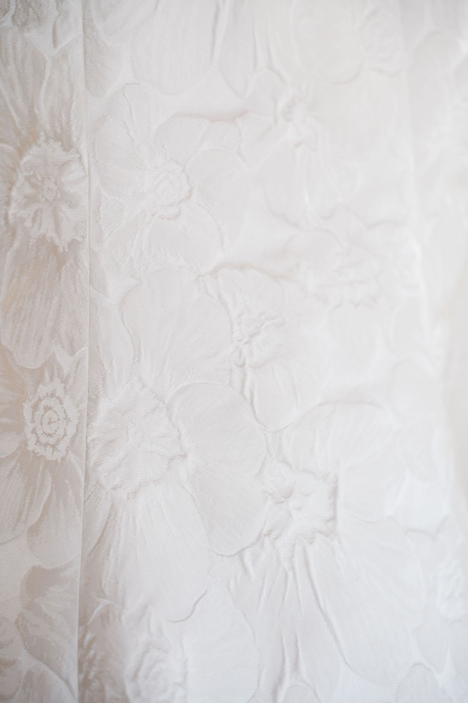 Delicate floral pattern on light beige wallpaper with subtle damask design creates an elegant vintage aesthetic.