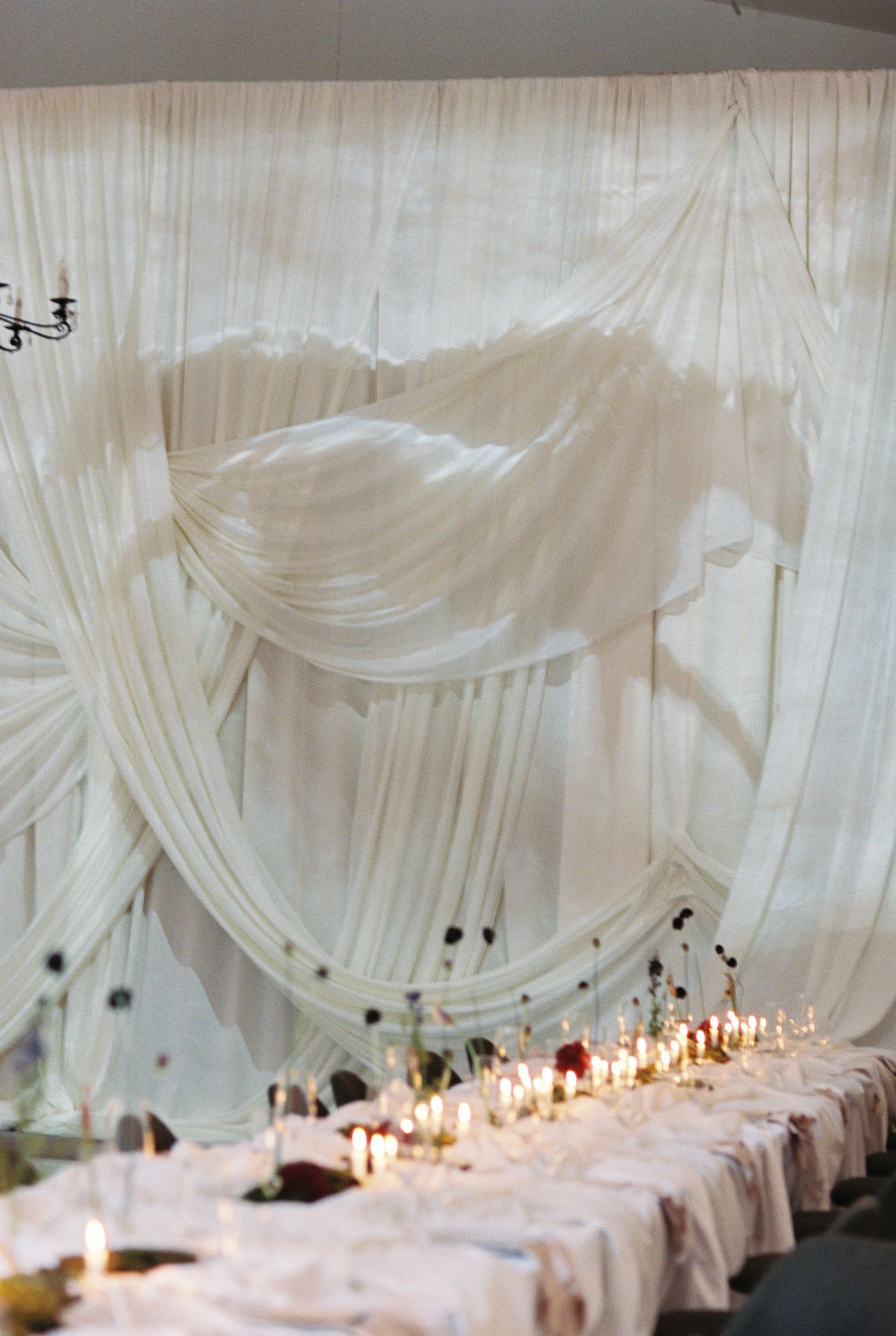 Elegant white draped fabric canopy over a dining table with glowing candlelight creating a romantic ambiance.