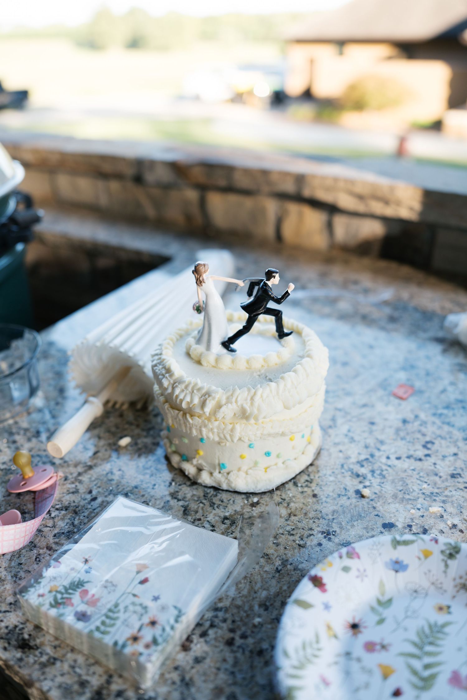 A series of wedding cake toppers arranged on a textured surface with decorative floral cards and confetti.