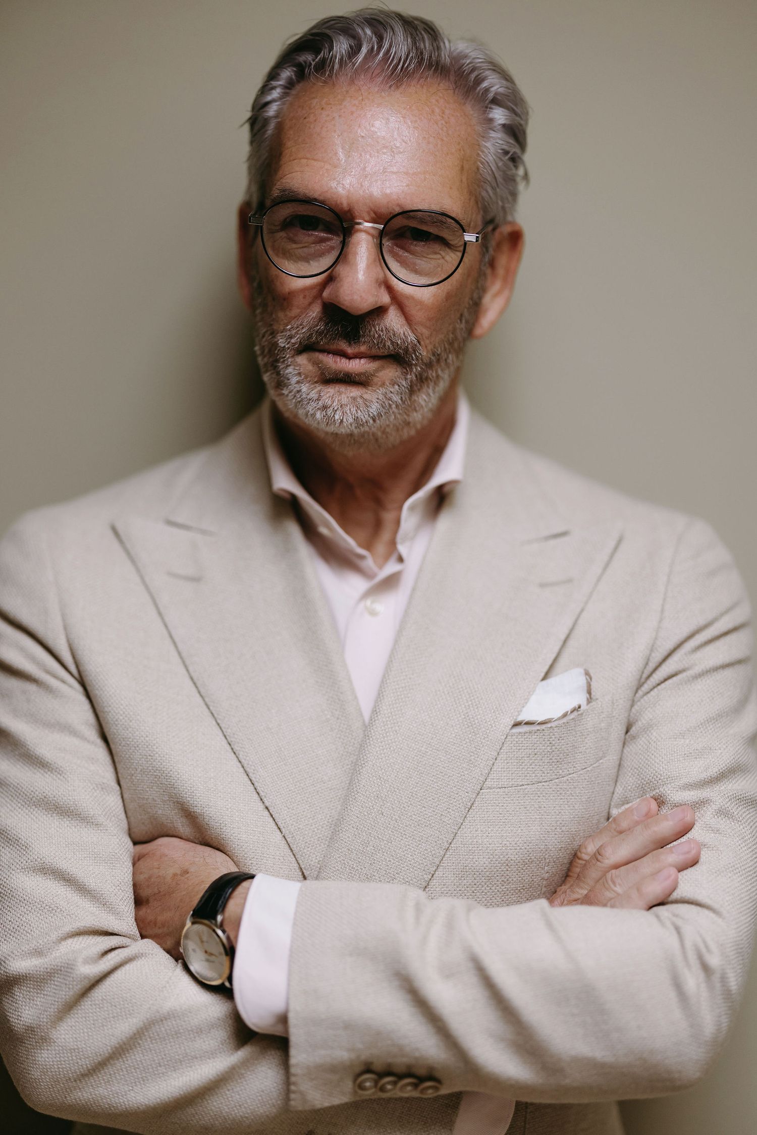 Portrait series of a distinguished gentleman in a light beige suit and glasses.
