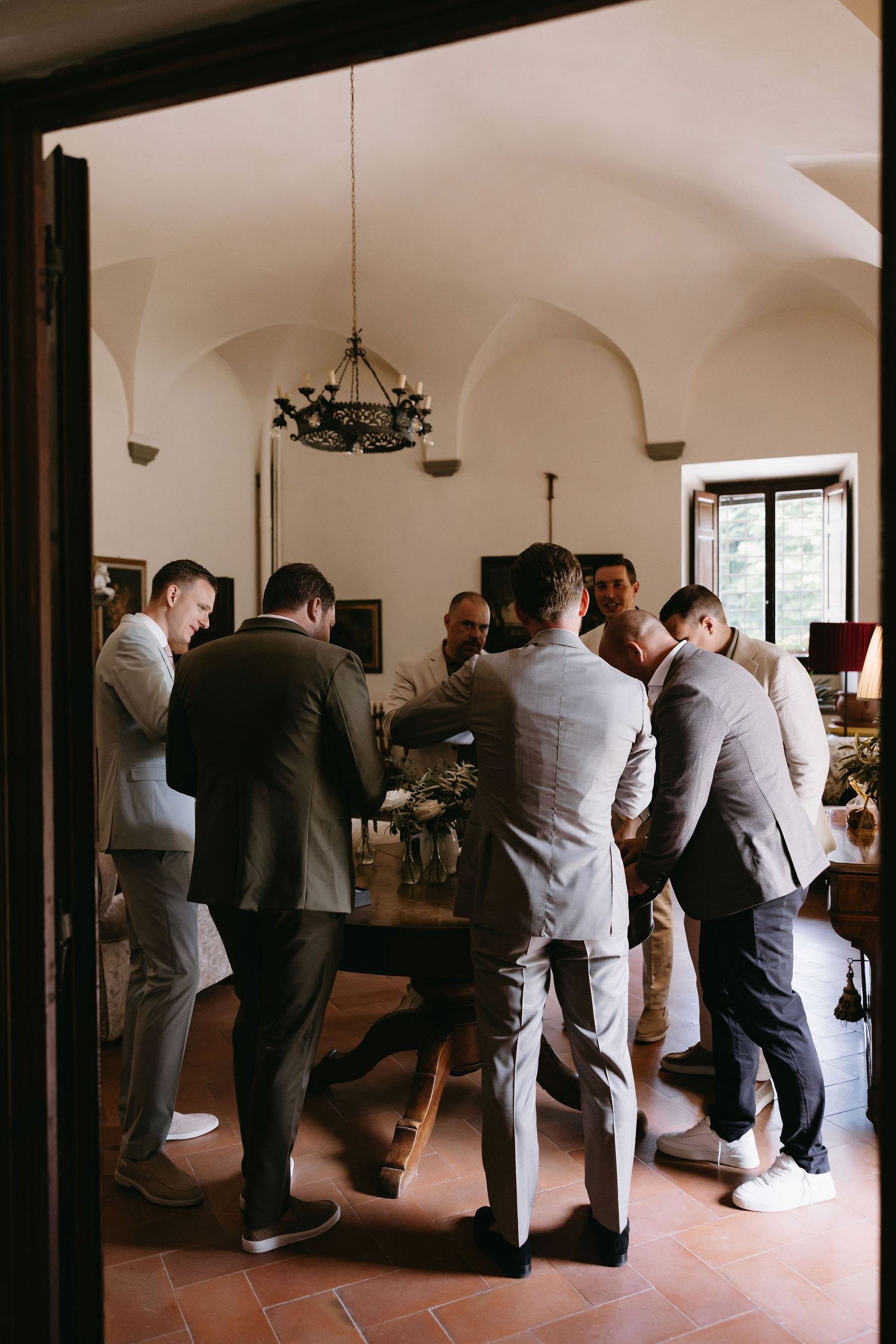 Group of formally dressed guests gathered at indoor bar during wedding reception.