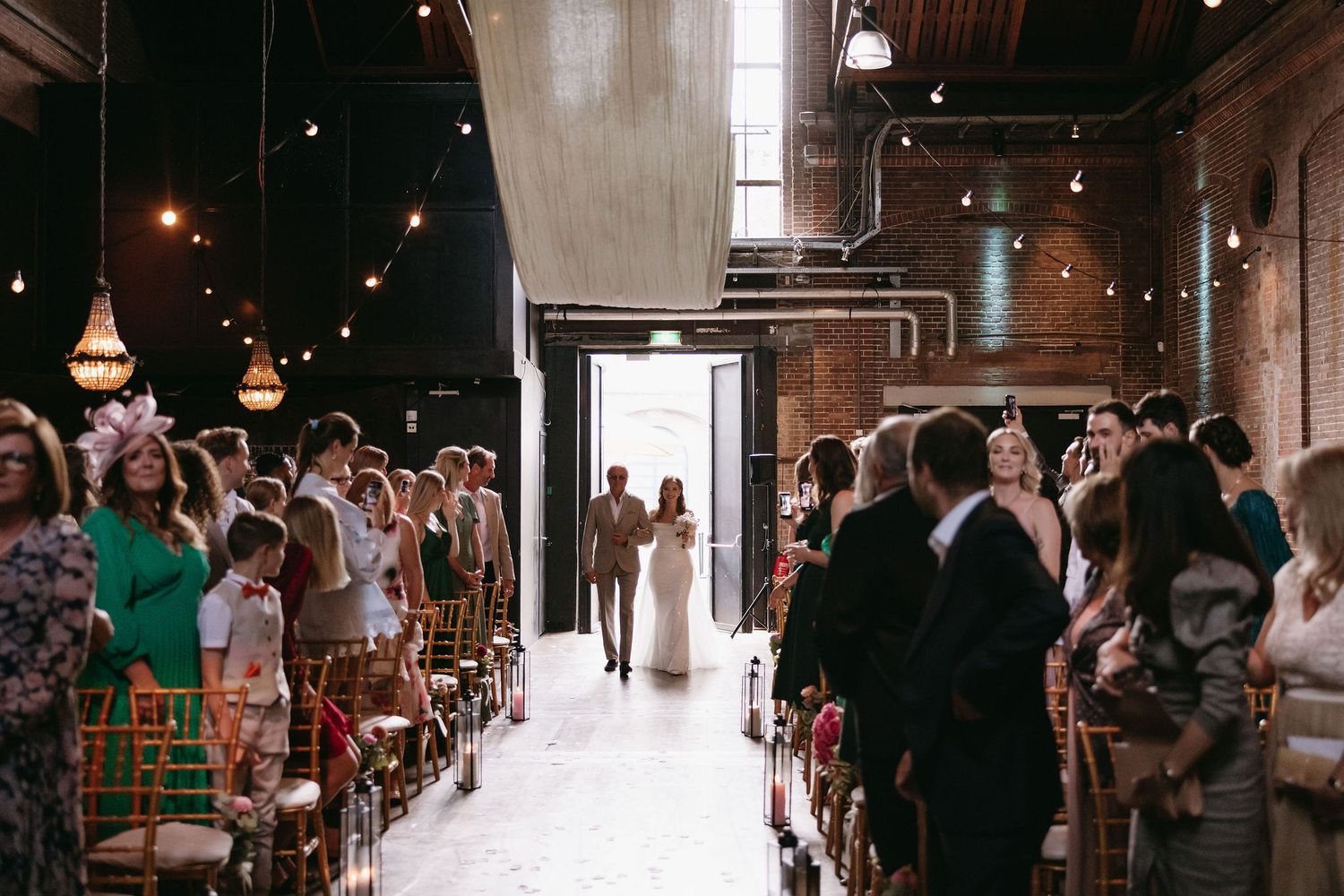 Industrial-style venue with string lights and wedding reception setup.