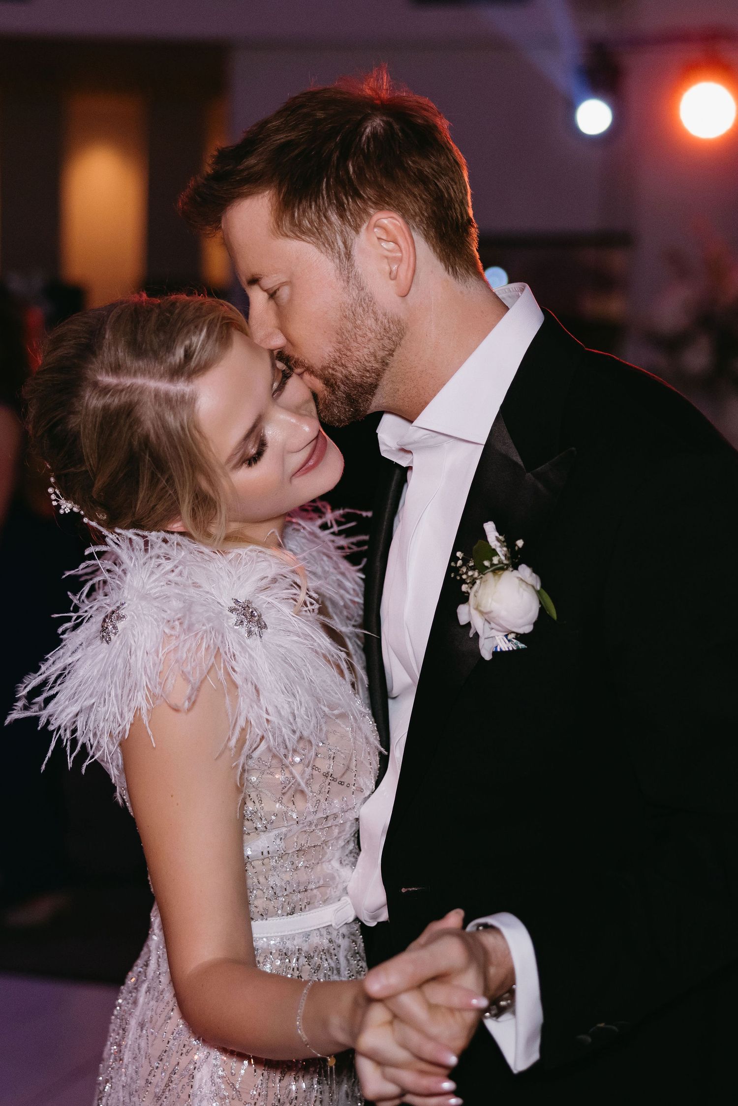 Couple sharing intimate dance moment under moody lighting at reception.