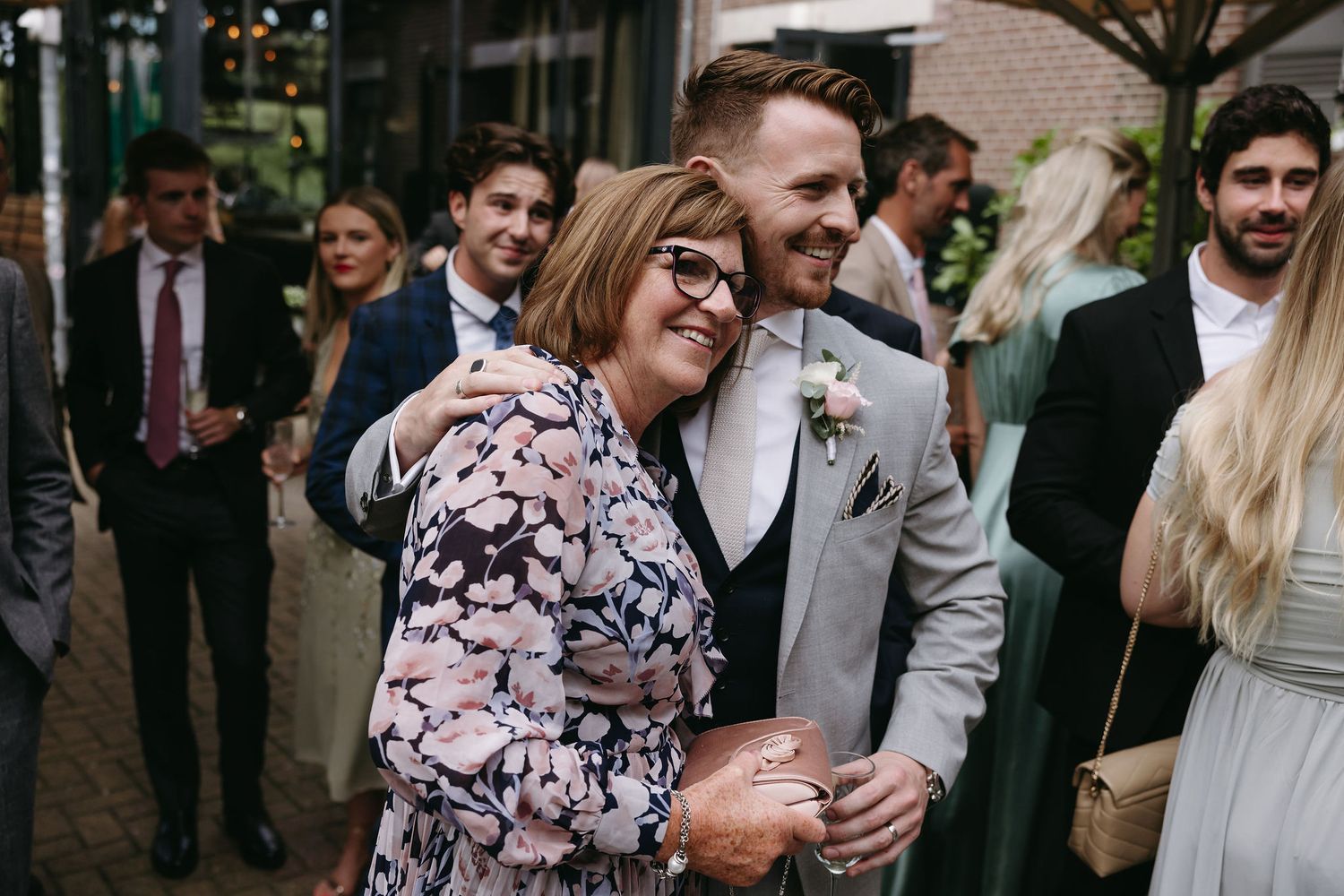 Wedding attendees share a candid laughing moment outside the venue in formal attire.