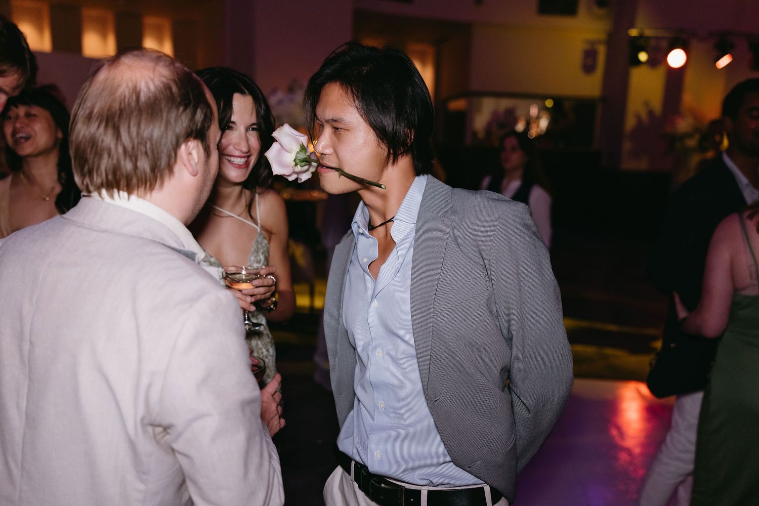 Wedding guests engaged in conversation at a dimly lit reception venue.