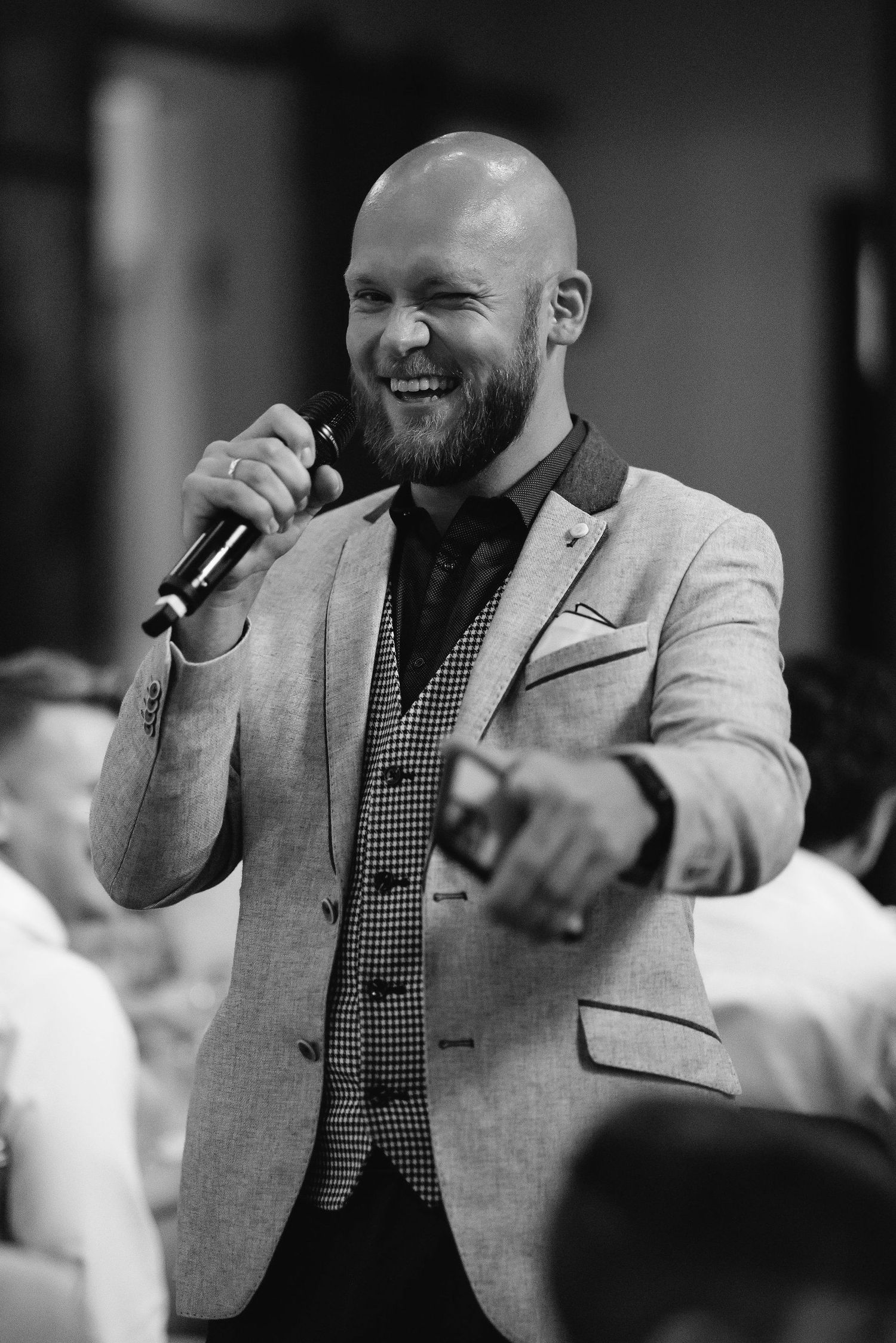 Speaker in grey blazer giving an animated speech at formal event.