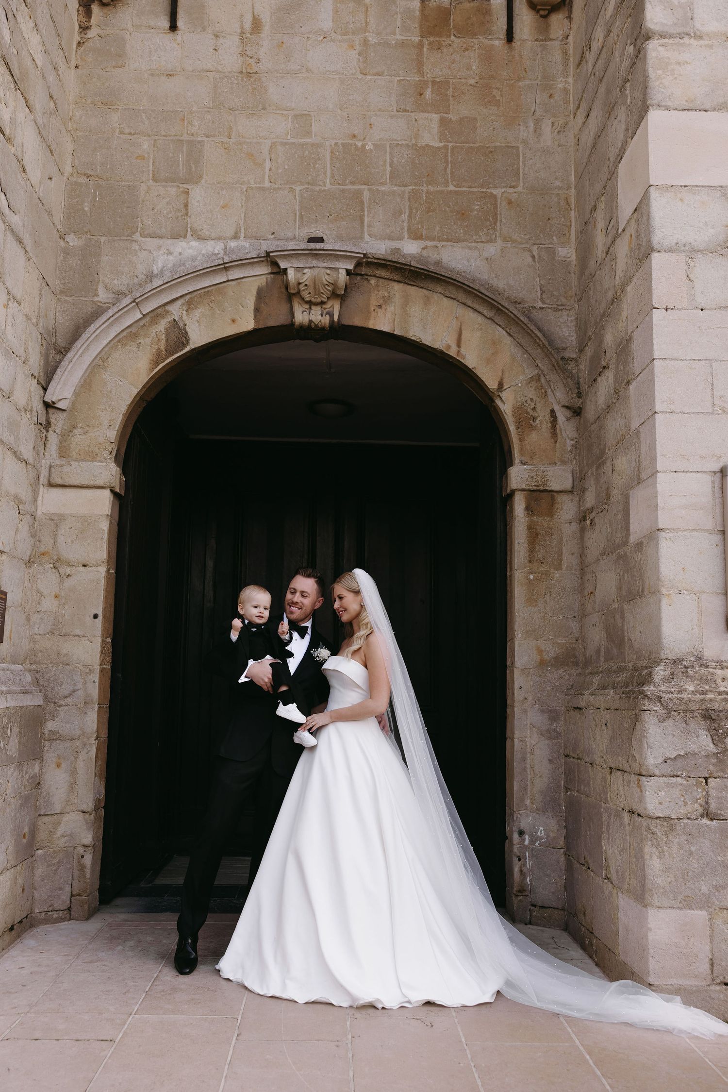 A wedding couple poses in a series of elegant stone archways for romantic portraits.