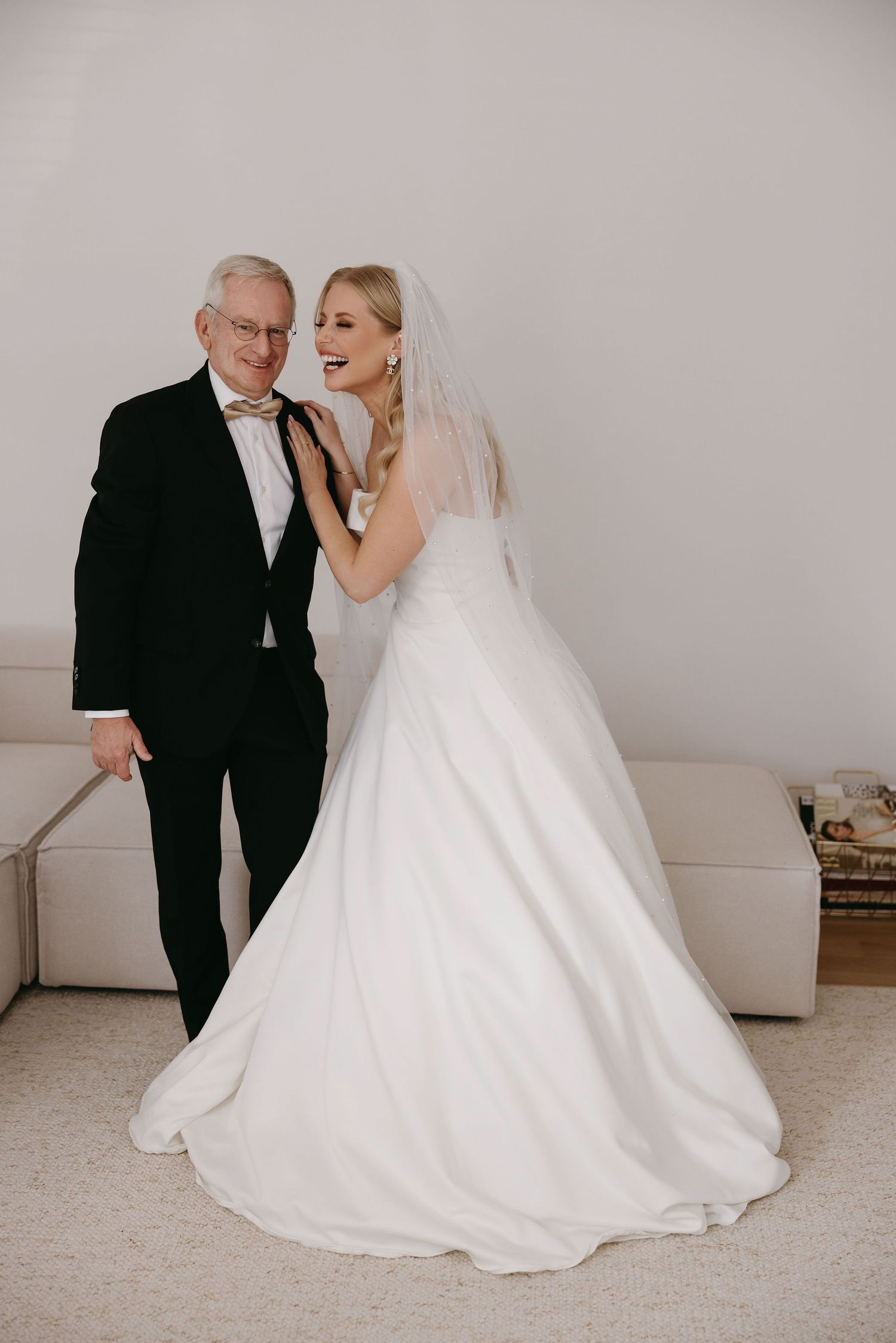 Wedding portrait featuring formal attire and flowing white gown against neutral background.